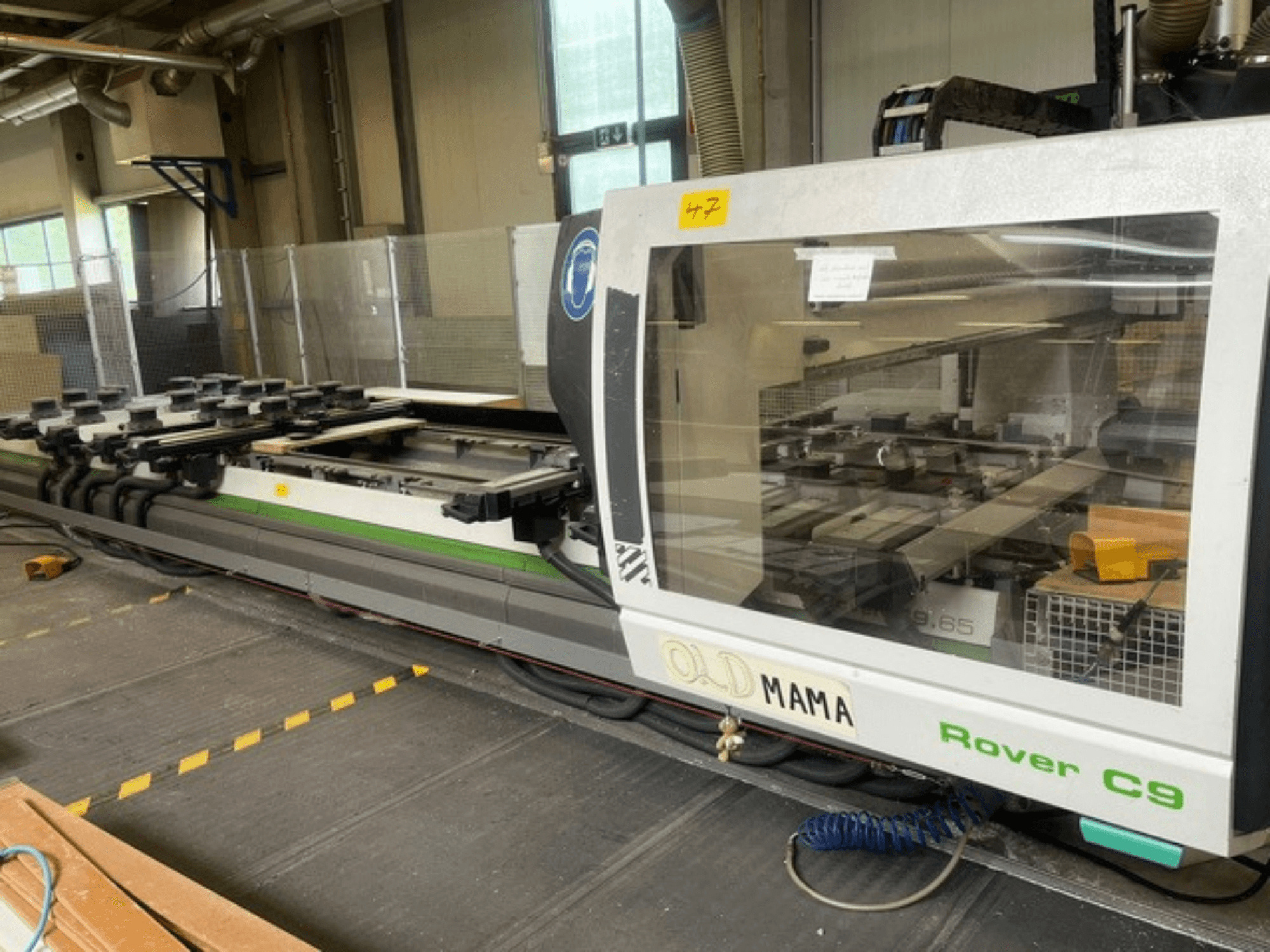 CNC glodalica BIESSE Rover C 9.65 u radionici, bočni pogled koji prikazuje upravljačku ploču i radni stol sa stezaljkama.
