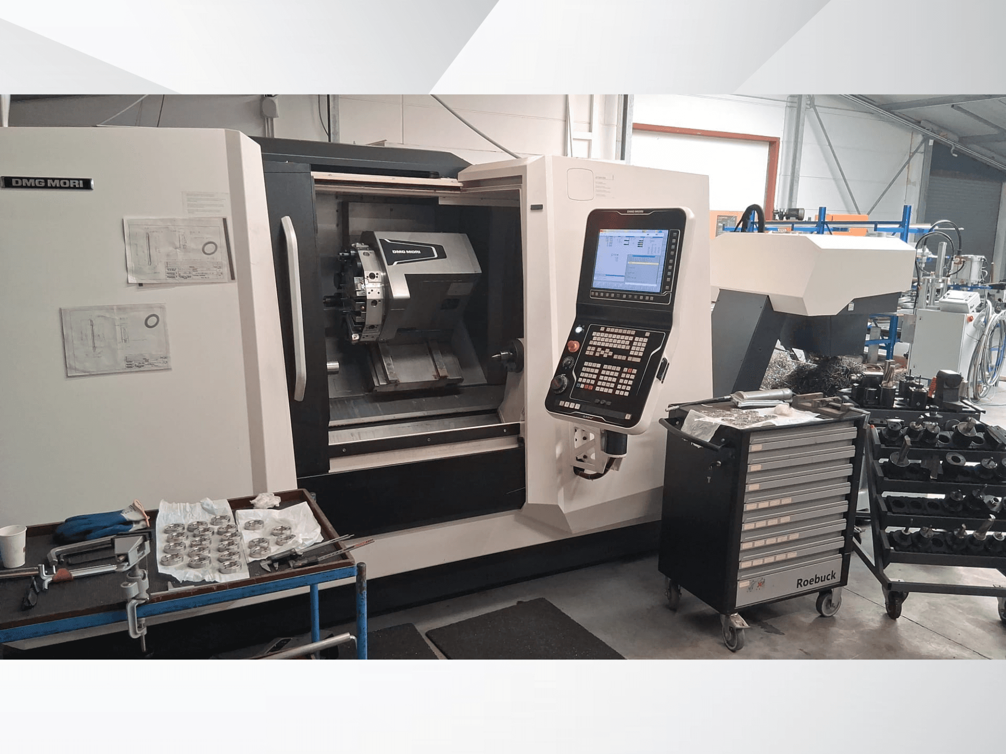 Horizontalni tokarski stroj DMG MORI CLX450 s prednje strane, s upravljačkom pločom, radnim prostorom, alatima i metalnim dijelovima.