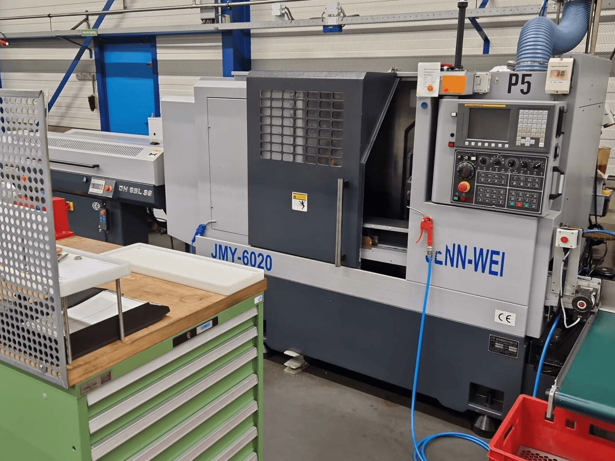 CNC tokarski stroj, model JMY-6020 proizvođača cNN-WEI, pogled sprijeda. Ima upravljačku ploču, zaustavljanje u nuždi i cijev za rashladno sredstvo.