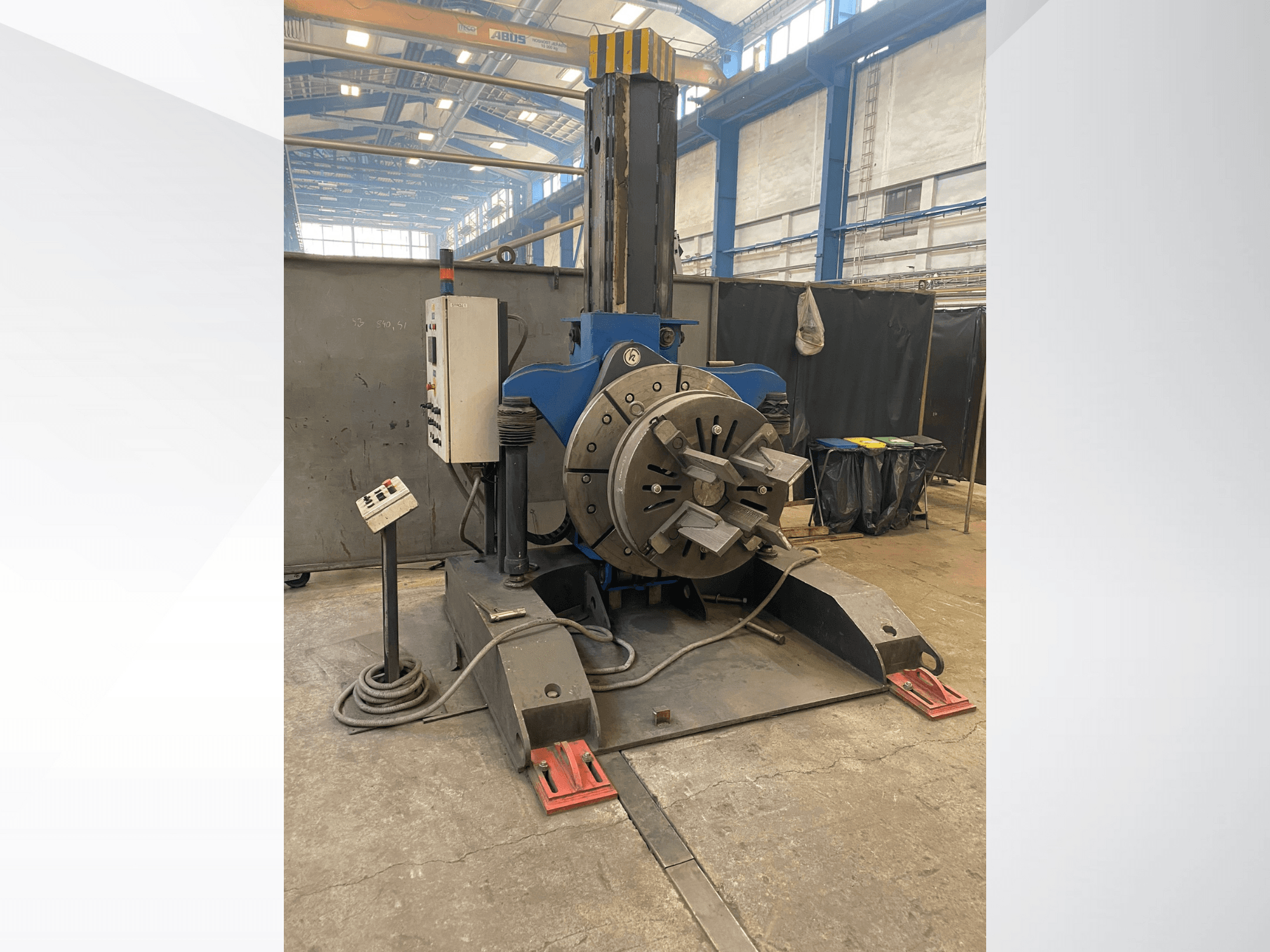 Plavi industrijski tokarski stroj s okruglom rotirajućom glavom i upravljačkom pločom, bočni pogled, u radioničkom okruženju.