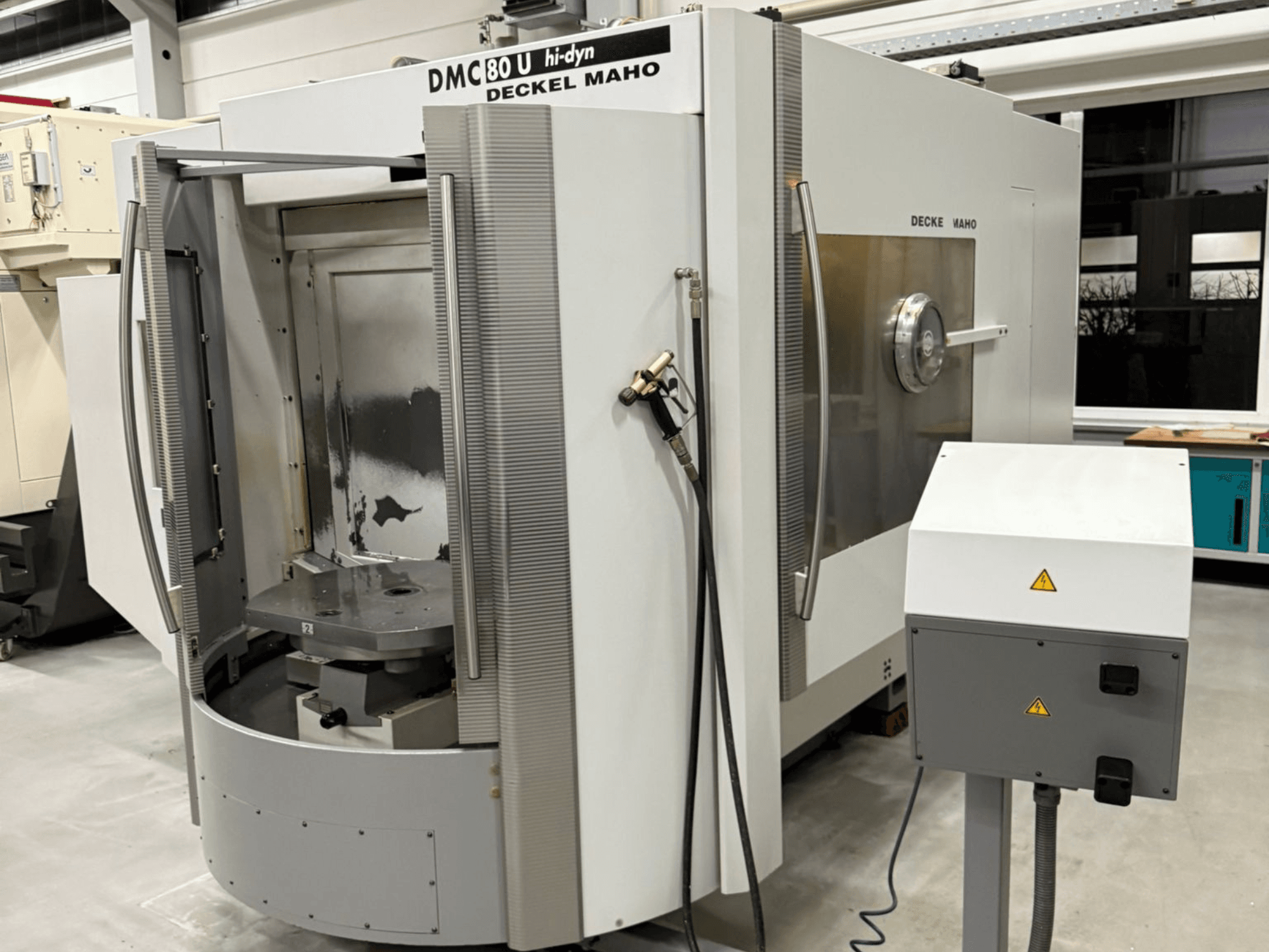 Prednji pogled na brzu CNC glodalicu Deckel Maho DMC 80 U, s otvorenim pristupnim vratima i bočnom upravljačkom pločom.
