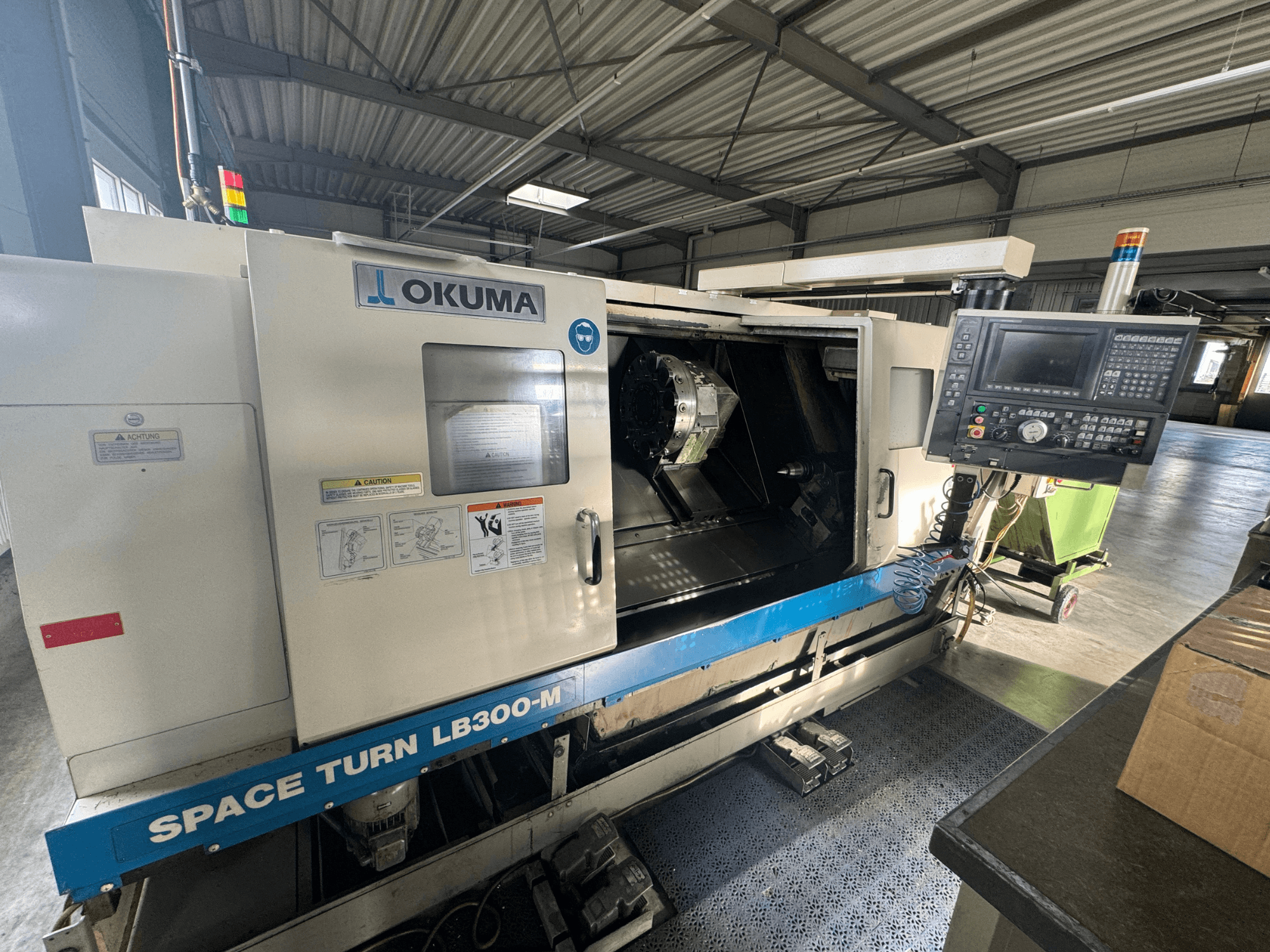 Okuma Space Turn LB300-M CNC tokarilica s prednje strane, s upravljačkom pločom i otvorenim vratima koja otkrivaju unutarnje područje obrade.