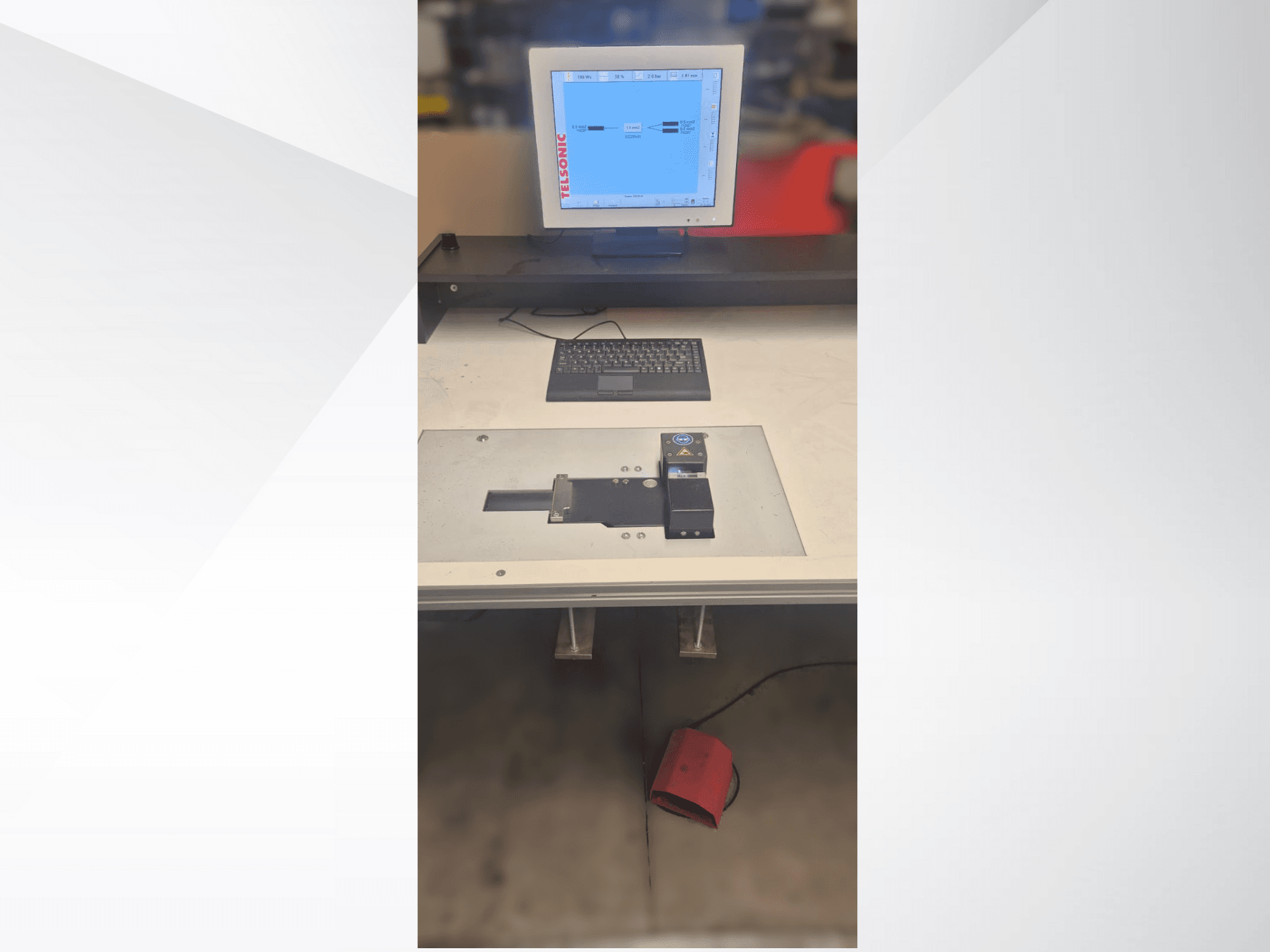 Pogled odozgo na ispitnu stanicu s računalnim monitorom, tipkovnicom i upravljačkom pločom s gumbom i zelenim svjetlom.