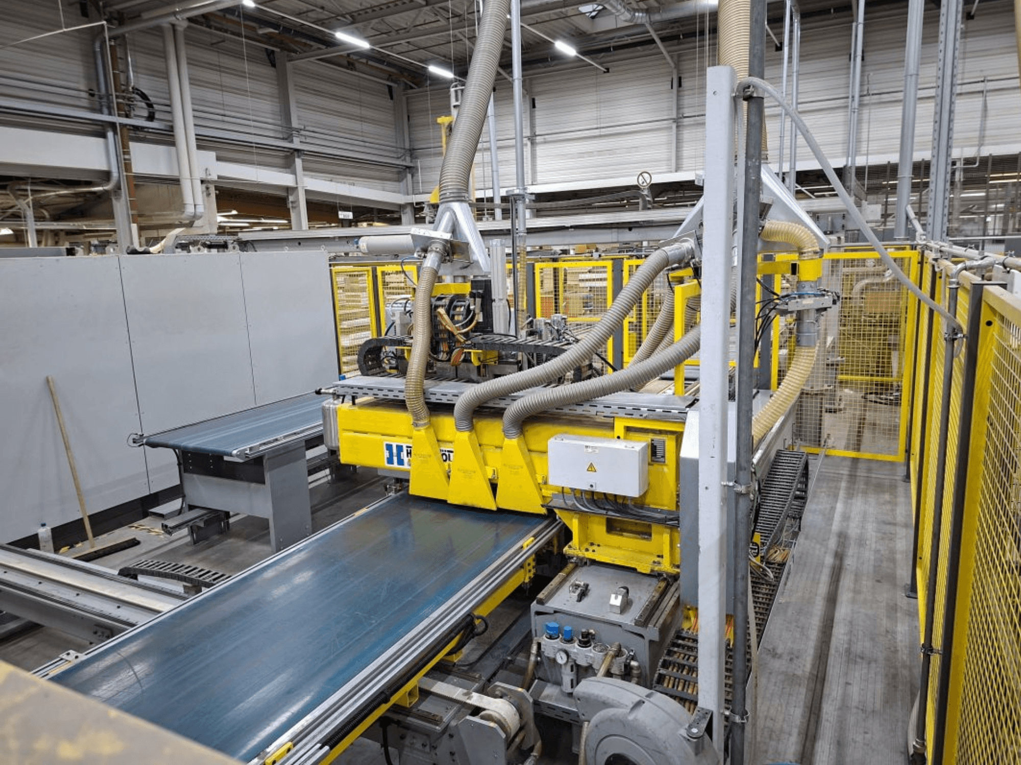 Industrijski transportni sustav iz bočnog prikaza, sa žutim strojevima, upravljačkom pločom i priključcima za crijeva za proizvodnju.