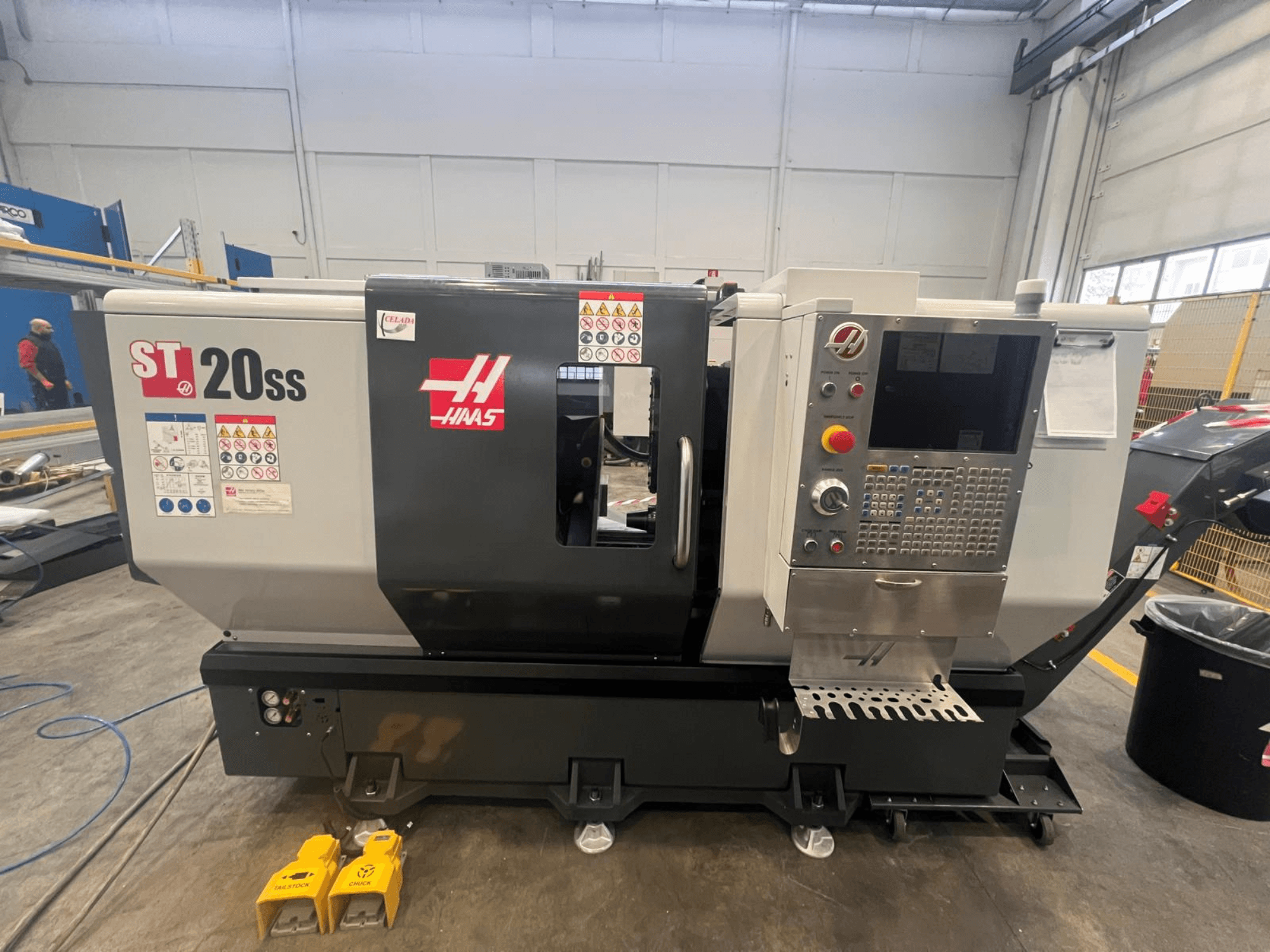 Haas ST 20SS CNC tokarilica u bočnom pogledu, s upravljačkom pločom, sigurnosnim naljepnicama i papučicama na podu.