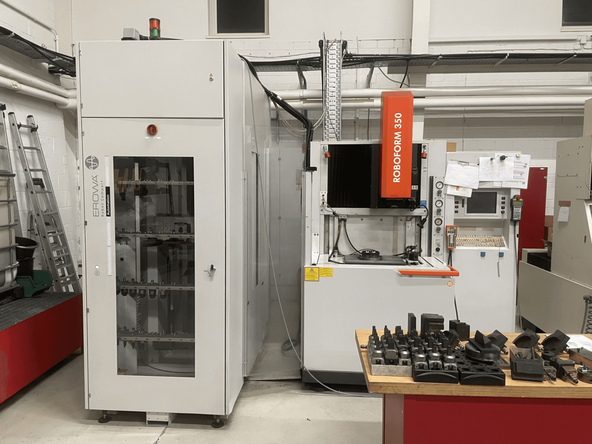 Stroj za eroziju udubljenjima CHARMILLES Roboform 350, prednji pogled, s alatima prikazanim na stolu i susjednom opremom.
