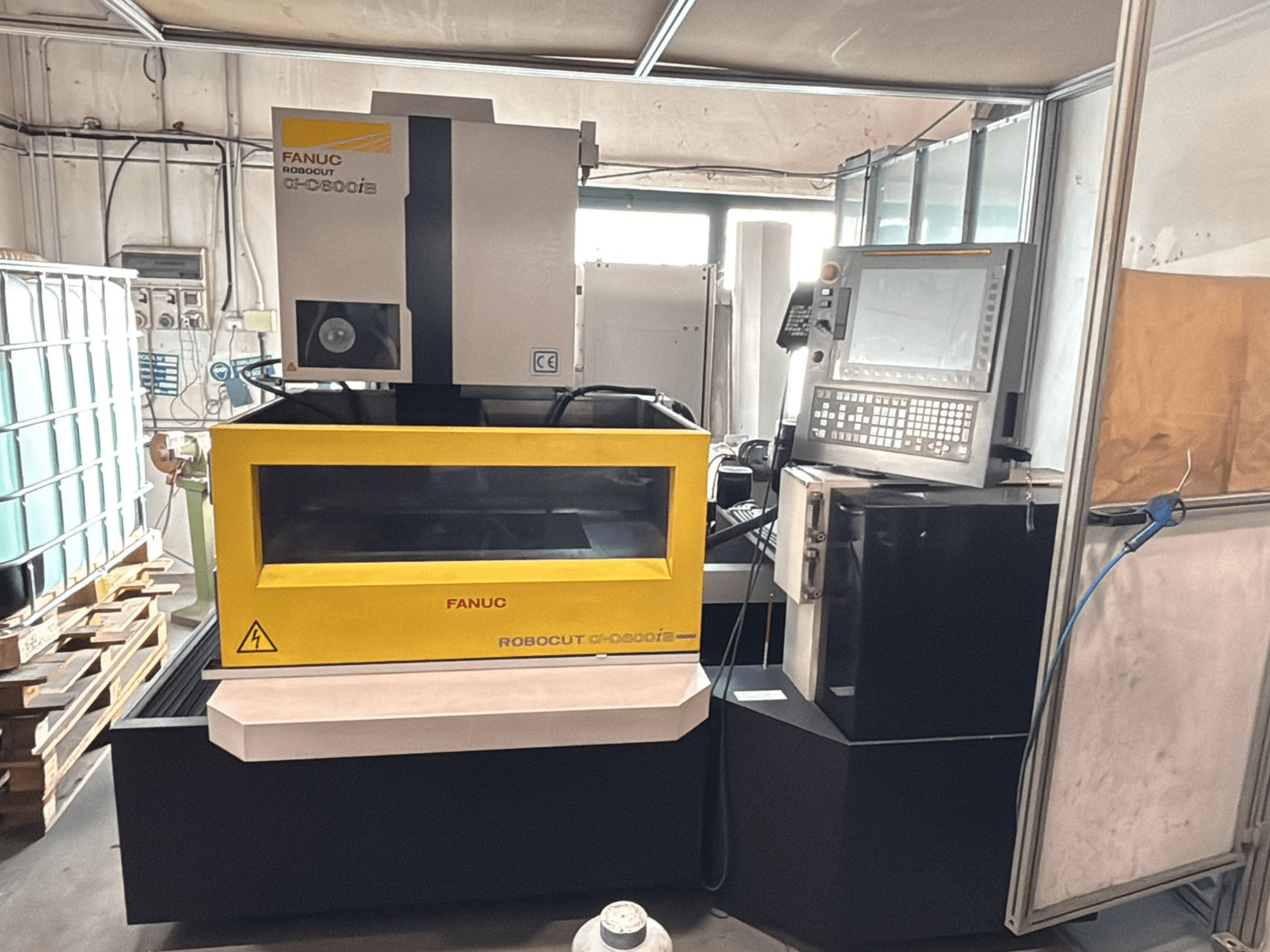 Prednji pogled na FANUC Robocut α-0iE CNC stroj sa žutim kućištem, na kojem se nalaze upravljačka ploča i zaslon.