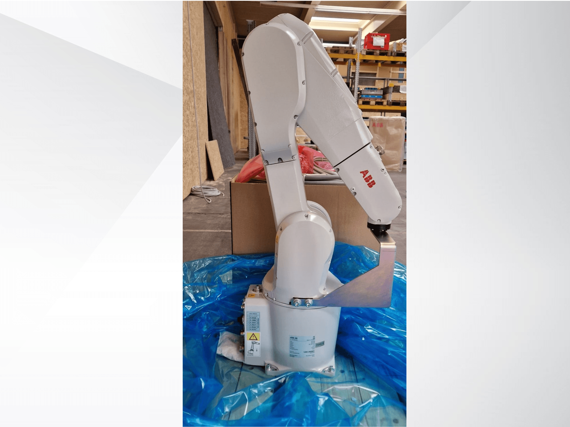 ABB model robotske ruke, bočni pogled na plavoj ceradi, s prikazom zglobnih spojeva i metalnog krajnjeg efektora, s vidljivim tehničkim oznakama.