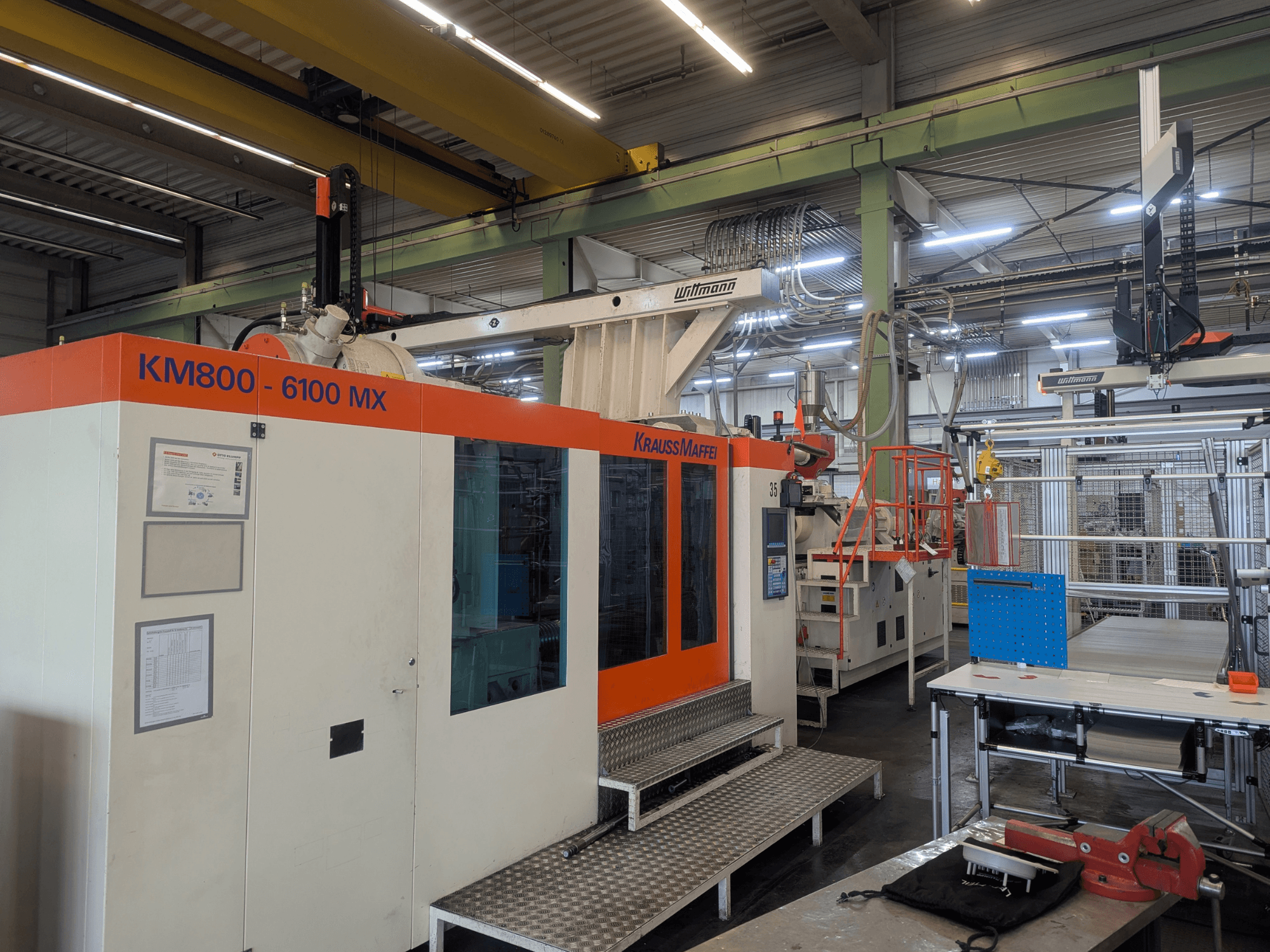 Krauss Maffei KM 800-6100MX hidraulični stroj za brizganje plastike, prednji pogled, prikaz upravljačke ploče i industrijske postavke.