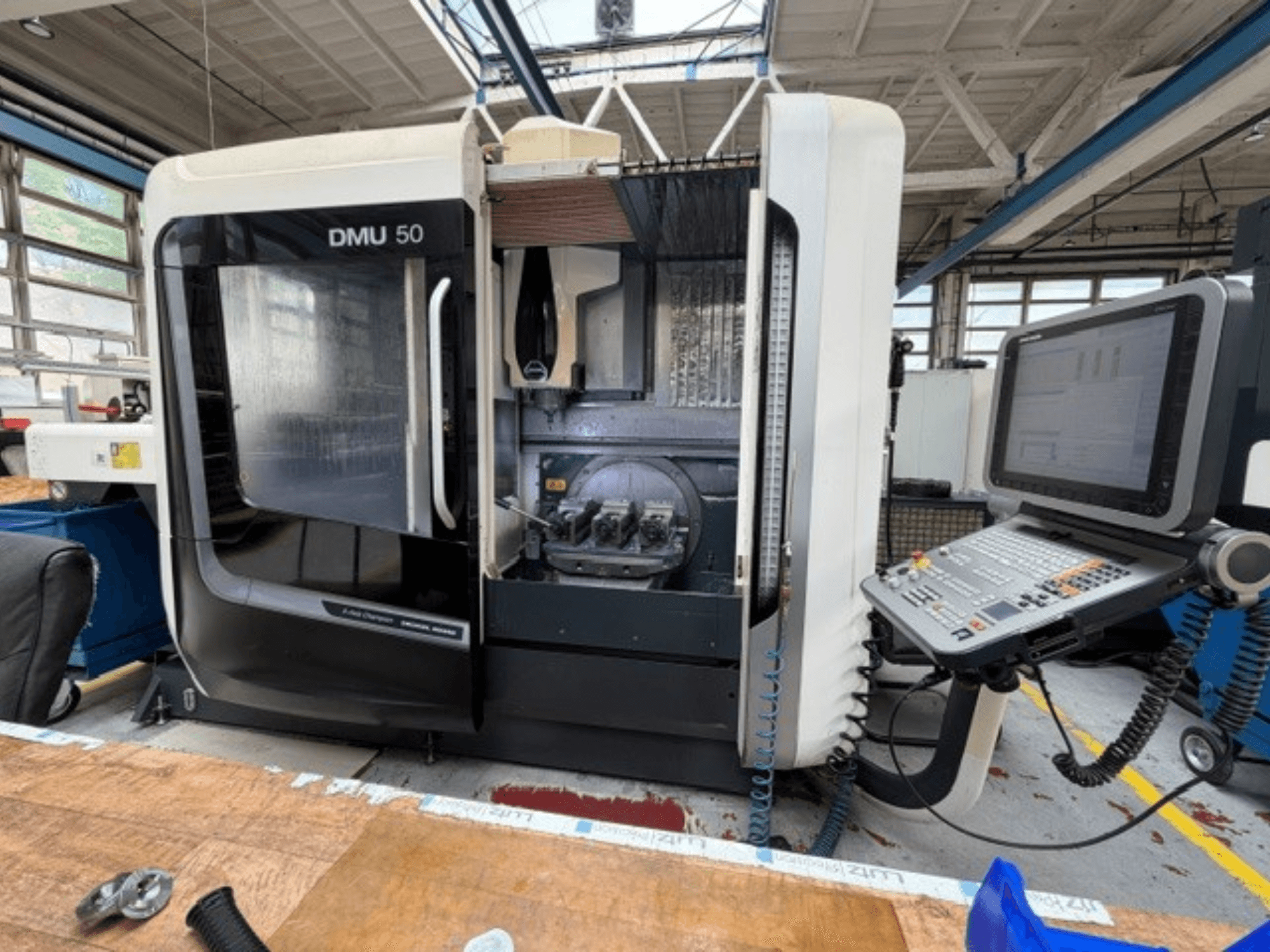 Vertikalni obradni centar DMG MORI DMU 50 3. generacije prikazan s prednje strane, s otvorenim vratima, vidljivom CNC upravljačkom pločom i radnim prostorom unutra.