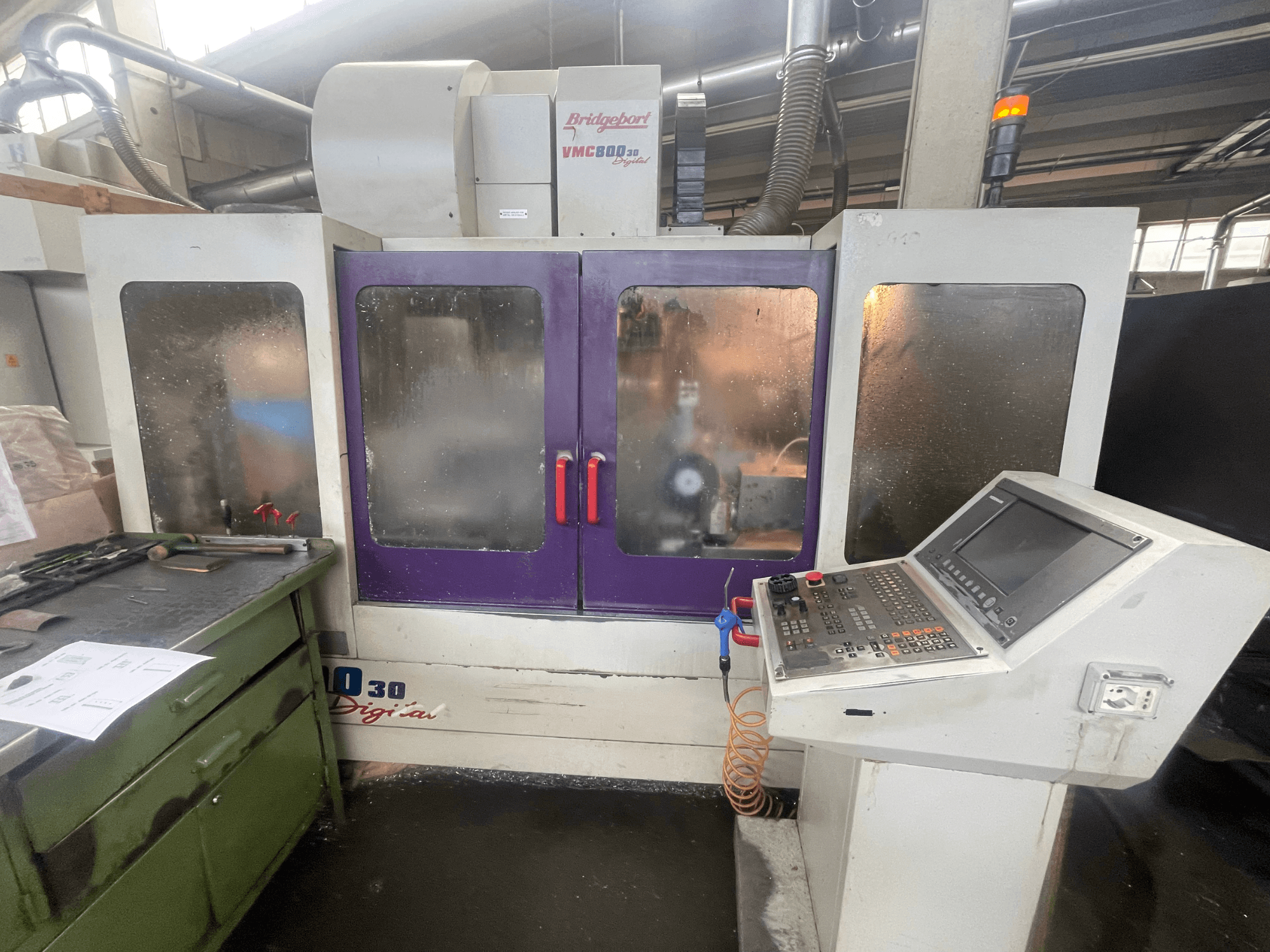 Vertikalni obradni centar Bridgeport VMC 800/30, prednji pogled, prikaz upravljačke ploče i ljubičastih vrata, alati na susjednoj površini.