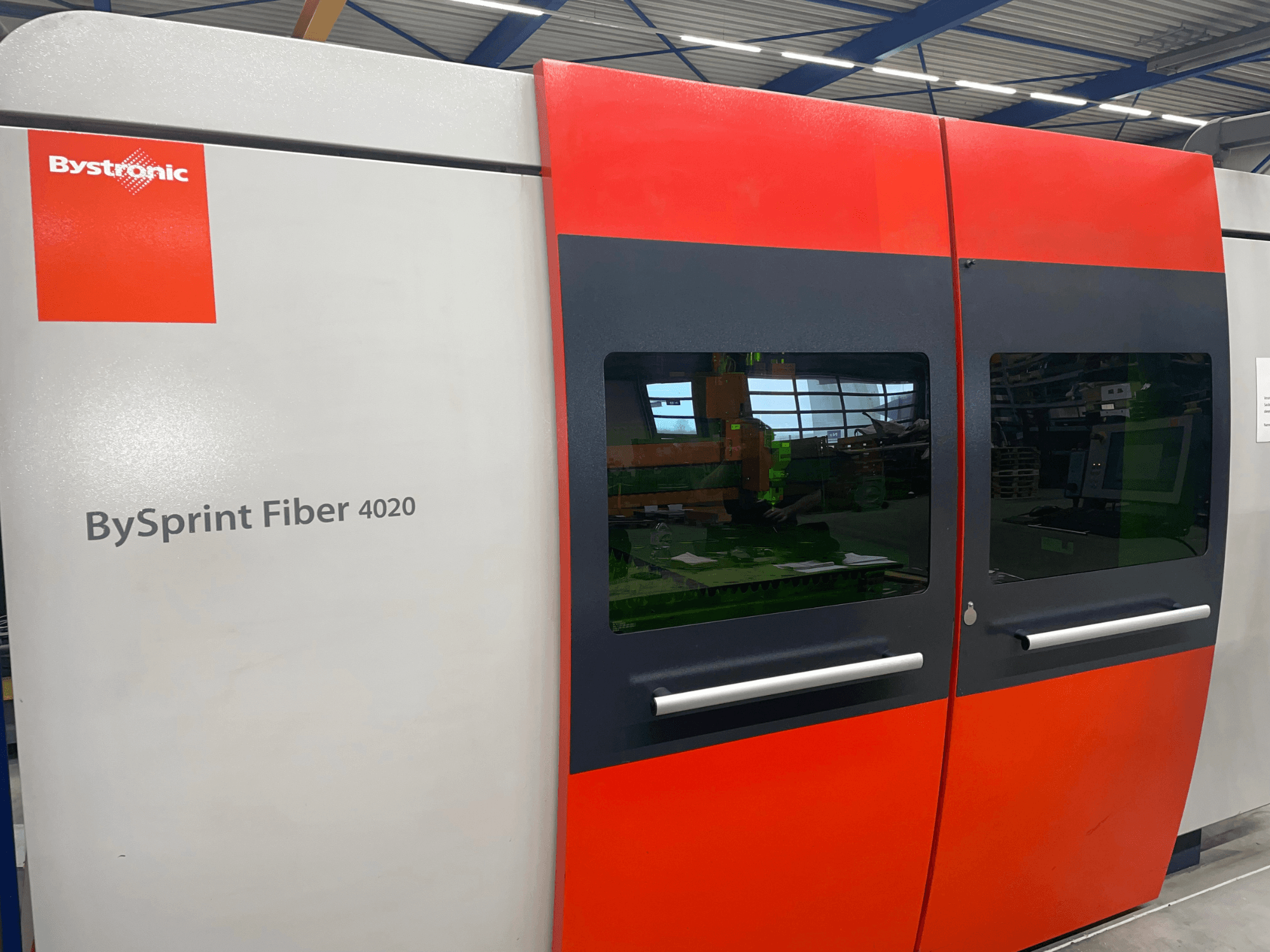 Bystronic BySprint Fiber 4020 u prednjem pogledu, sa sivo-crvenim dizajnom panela s velikim prozorima i vidljivim upravljačkim sučeljem iznutra.