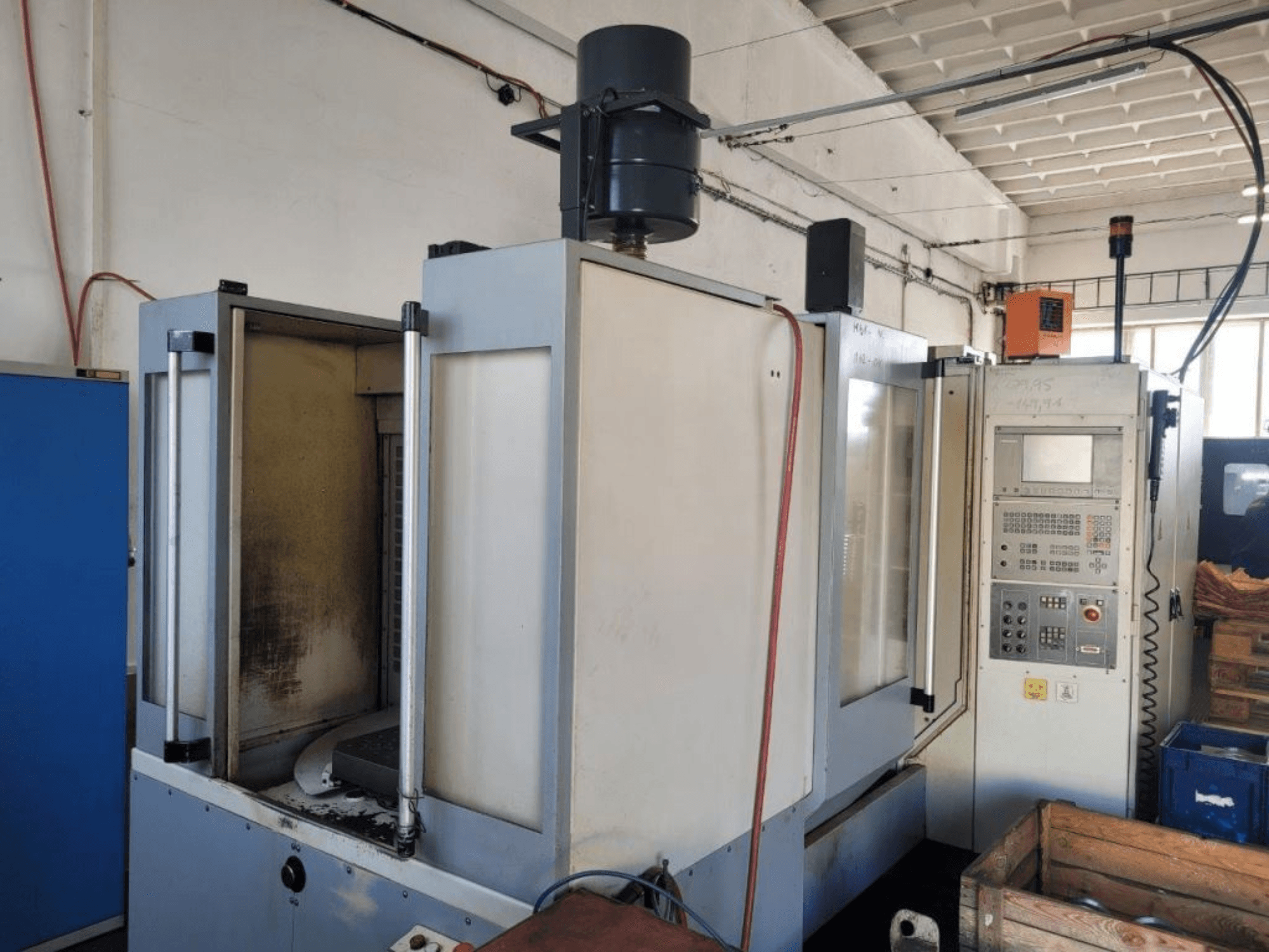 Industrijska CNC glodalica s upravljačkom pločom, bočni pogled, prikazuje kućište i vidljivu prljavštinu na površinama.