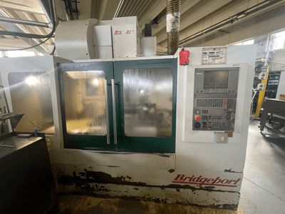 Vertikalni obradni centar Bridgeport VMC 1000/30, prednji pogled s upravljačkom pločom, na kojoj se vide istrošena vanjština i zelena vrata.