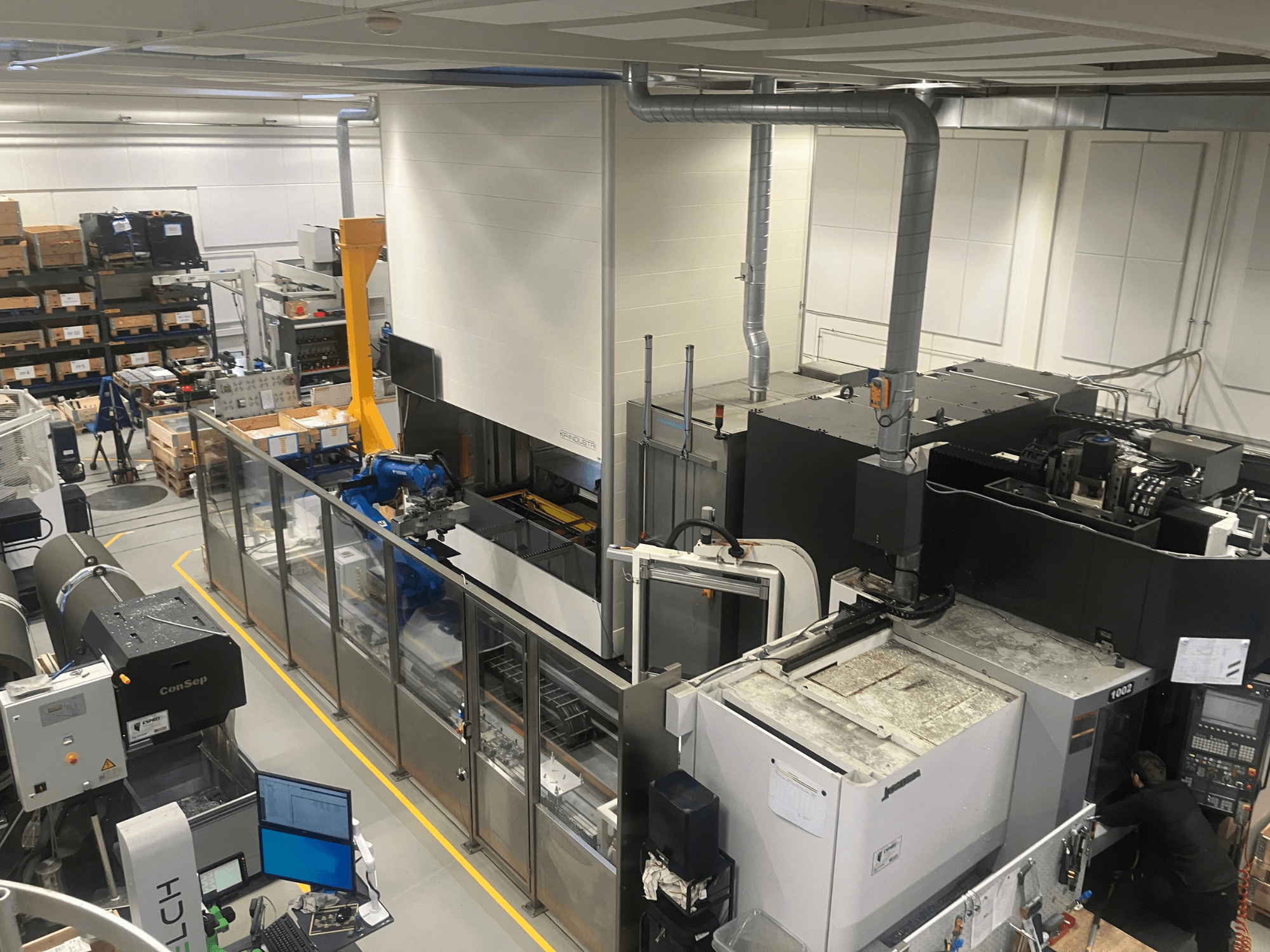 SSI SCHÄFER Logimat automatizacijski sustav u skladištu, pogled sprijeda; sadrži robotsku ruku, skladišne regale i strojeve.