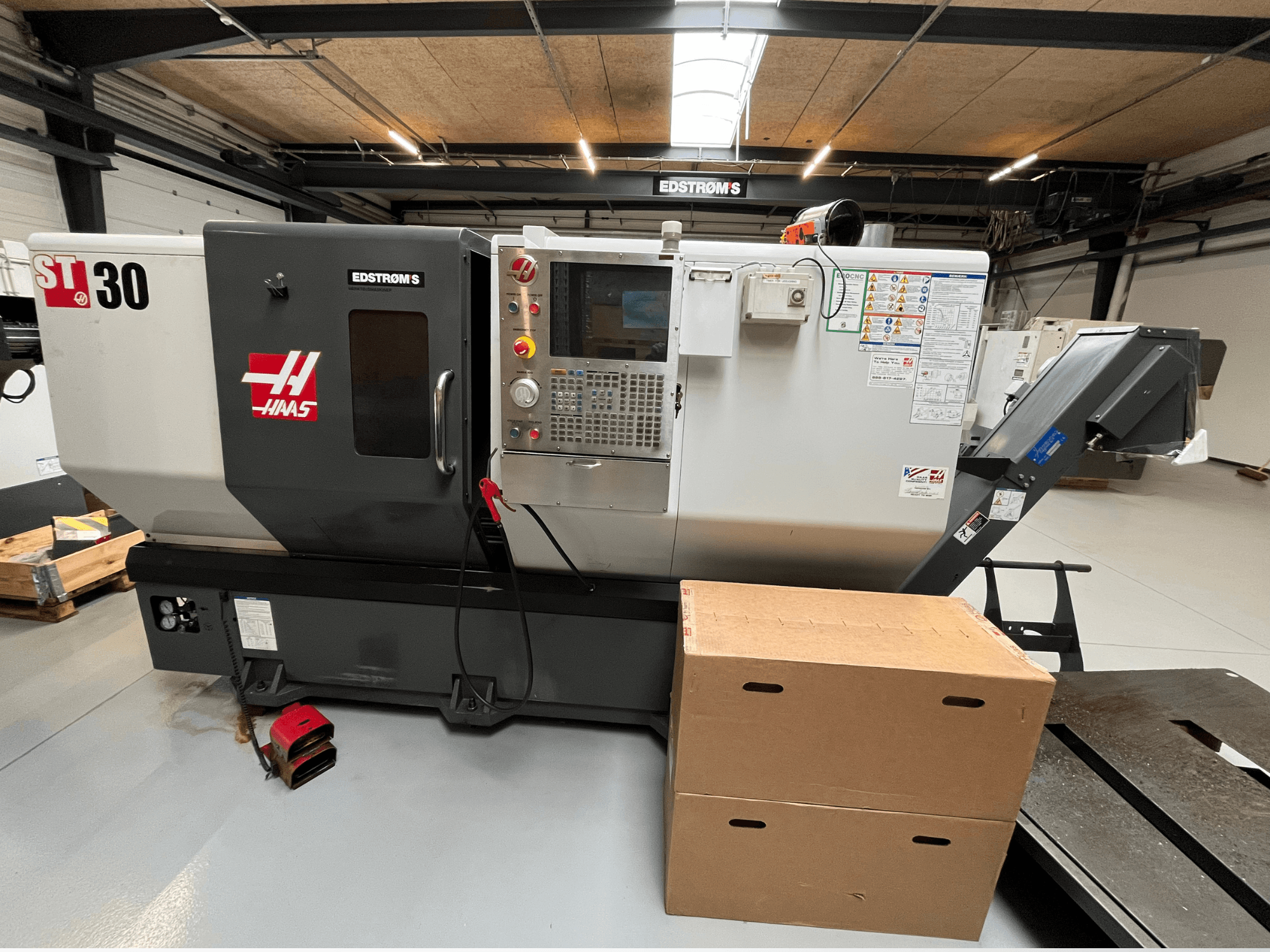 Haas ST-30 CNC tokarilica gledana sa strane, s upravljačkom pločom, značkom modela i dvije kartonske kutije u blizini.