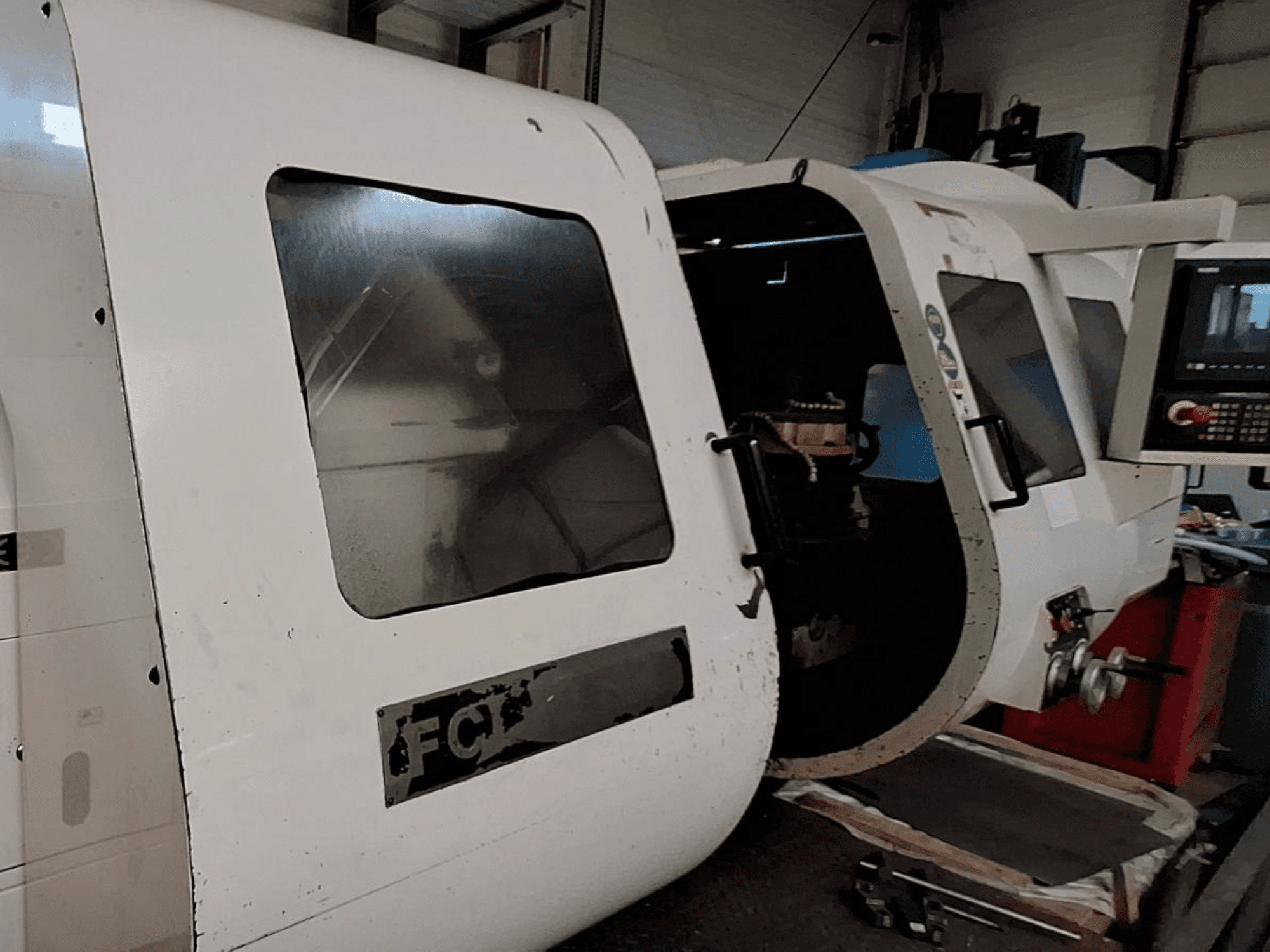 Bijeli CNC stroj s vidljivom upravljačkom pločom i otvorenim vratima, s vidljivim unutarnjim komponentama; prednji pogled. Marka: FCT.