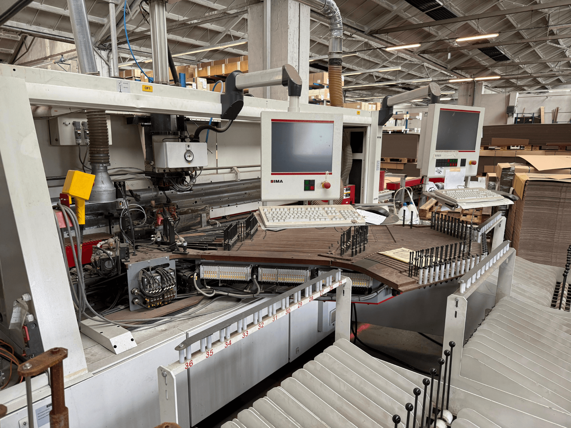 IMA precizni stroj za obradu drveta s dvostrukim monitorima i upravljačkim pločama, prednji pogled koji prikazuje transporter i područje alata.