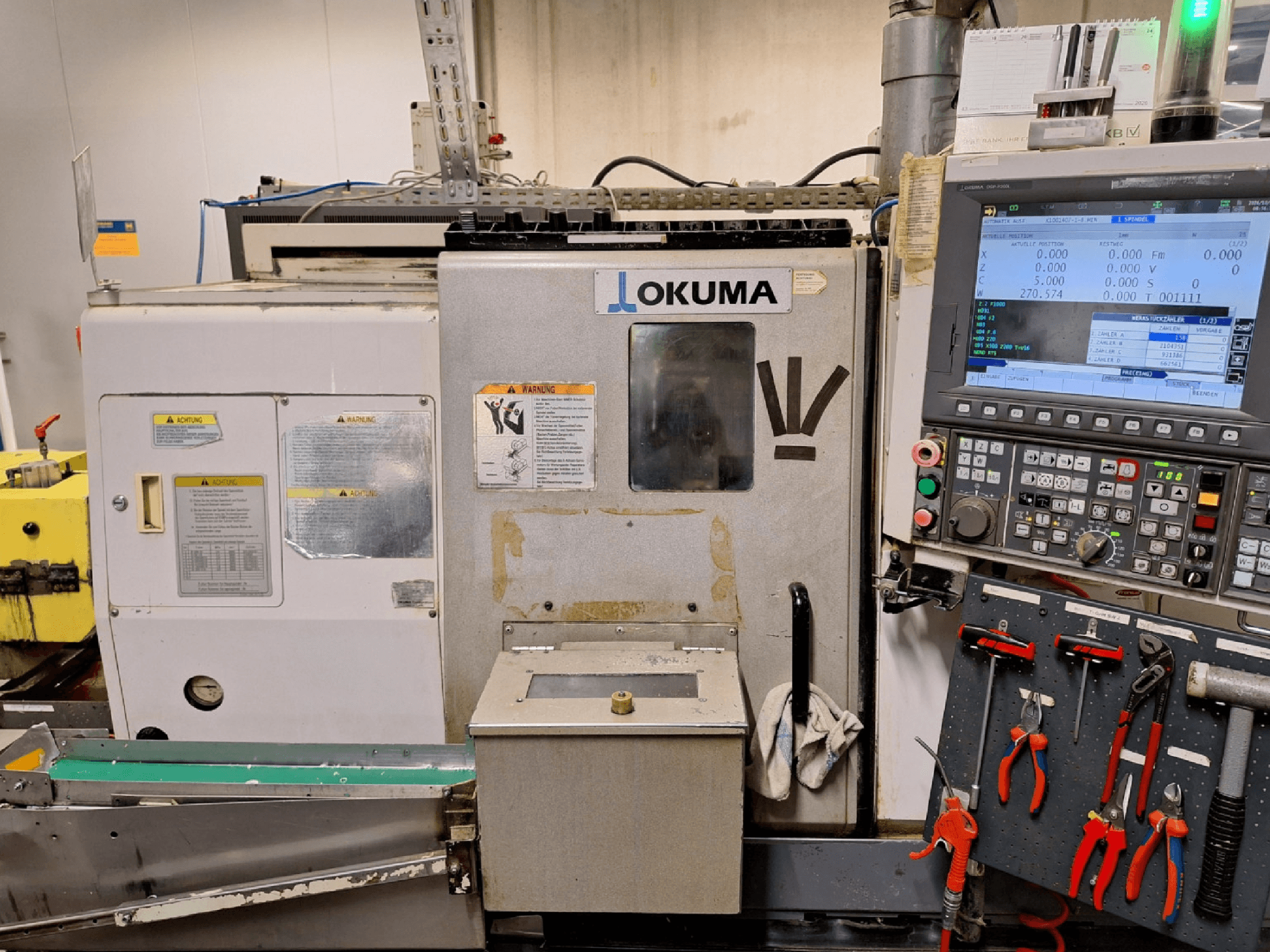 Horizontalni tokarski stroj Okuma LB200-MW, pogled sprijeda, s upravljačkom pločom i alatima vidljivim sa strane.