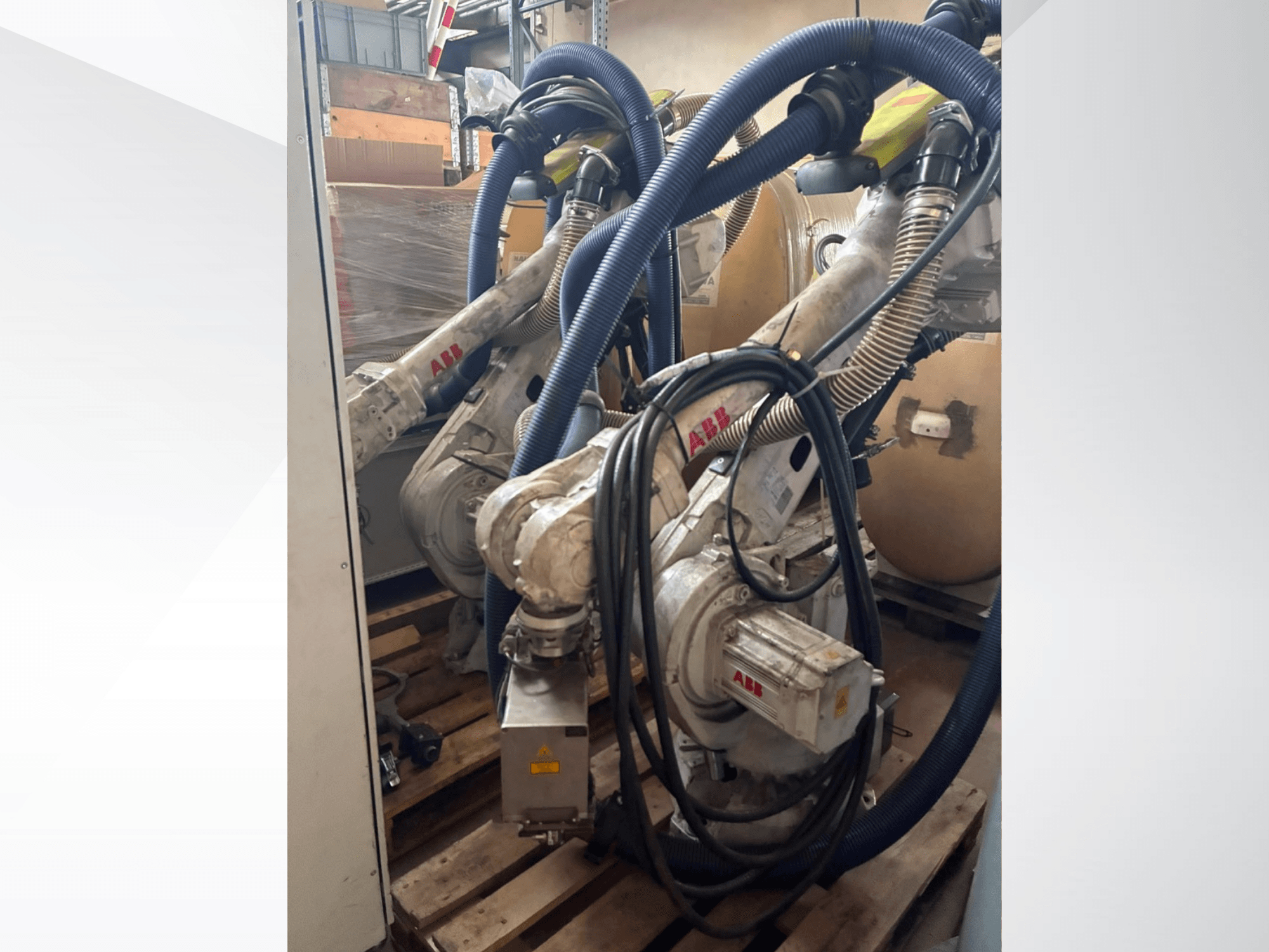 ABB IRB 4600-40/2.55 robotska ruka, bočni pogled koji prikazuje dvostruke ruke i priključena crijeva, montirane na palete u skladišnom okruženju.