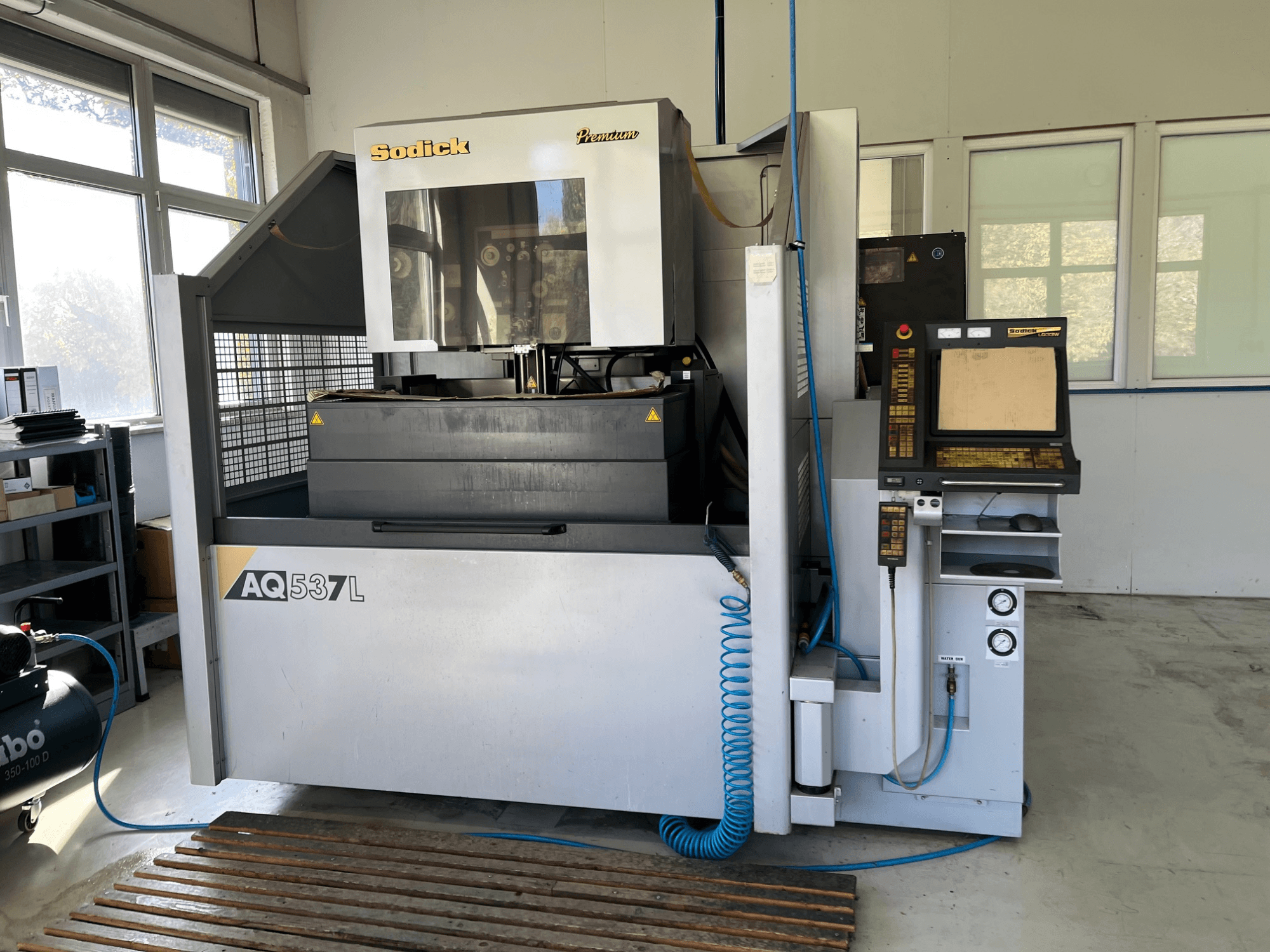 Sodick AQ537L elektroerozivni stroj (EDM) u prednjem pogledu, s upravljačkom pločom, vodovima za vodeno hlađenje i radnim prostorom.
