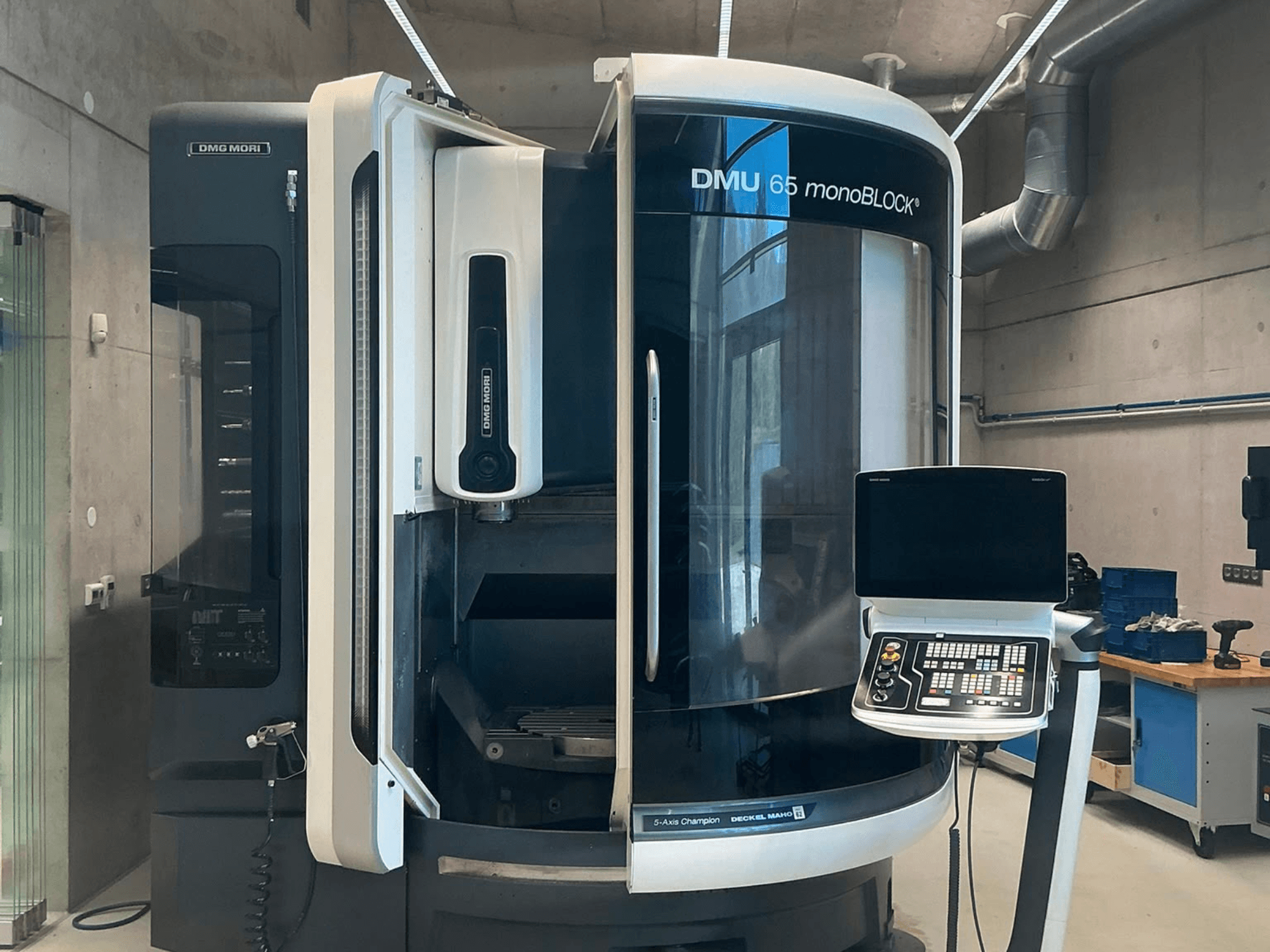 Vertikalni obradni centar DMG MORI DMU 65 monoBLOCK, prednji pogled, prikazuje upravljačku ploču i detalje stroja u radioničkom okruženju.