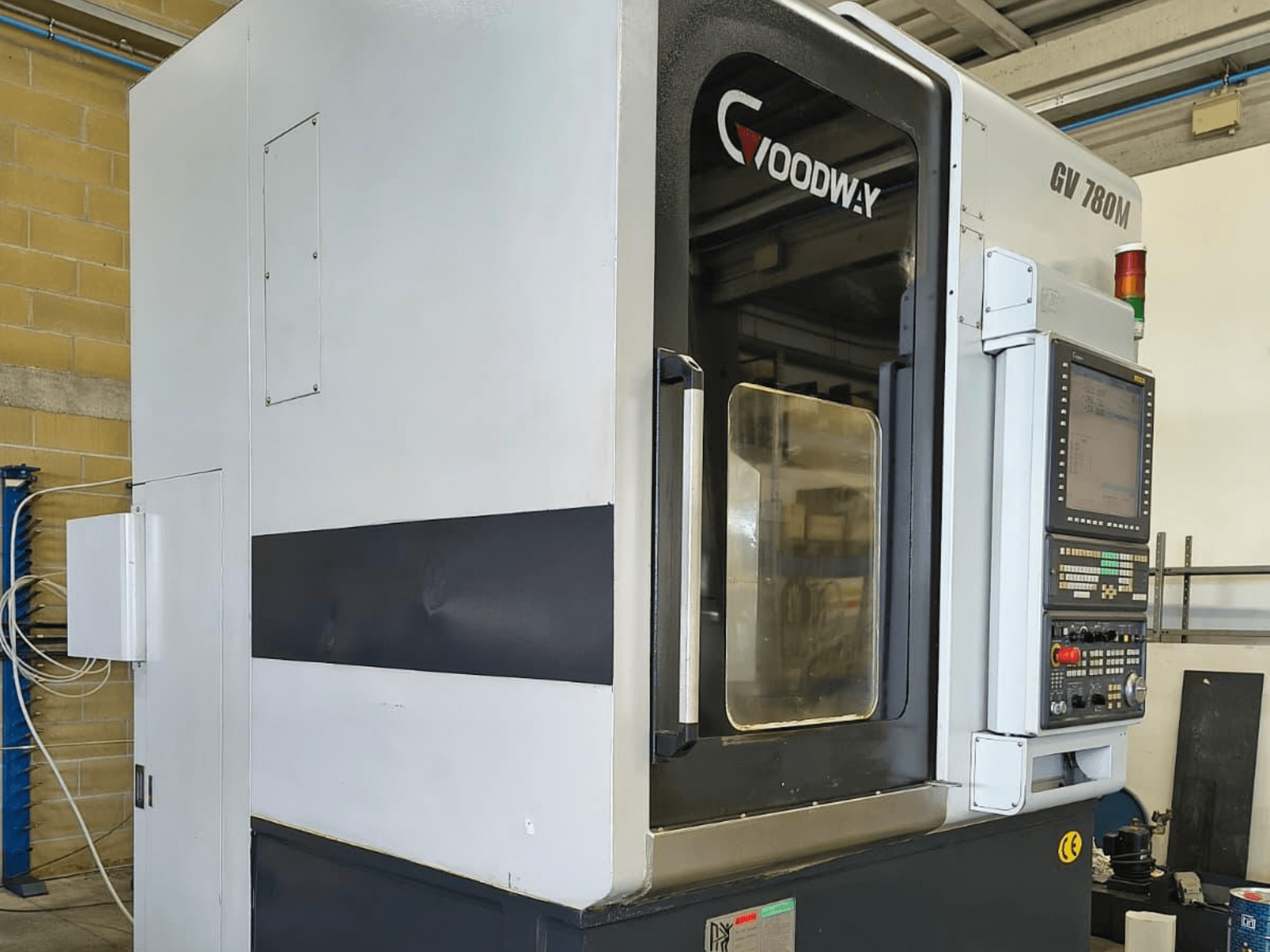 Vertikalna tokarska mašina Goodway GV 780 M, bočni pogled, prikaz upravljačke ploče, sigurnosnih značajki i čistog vanjskog dizajna.