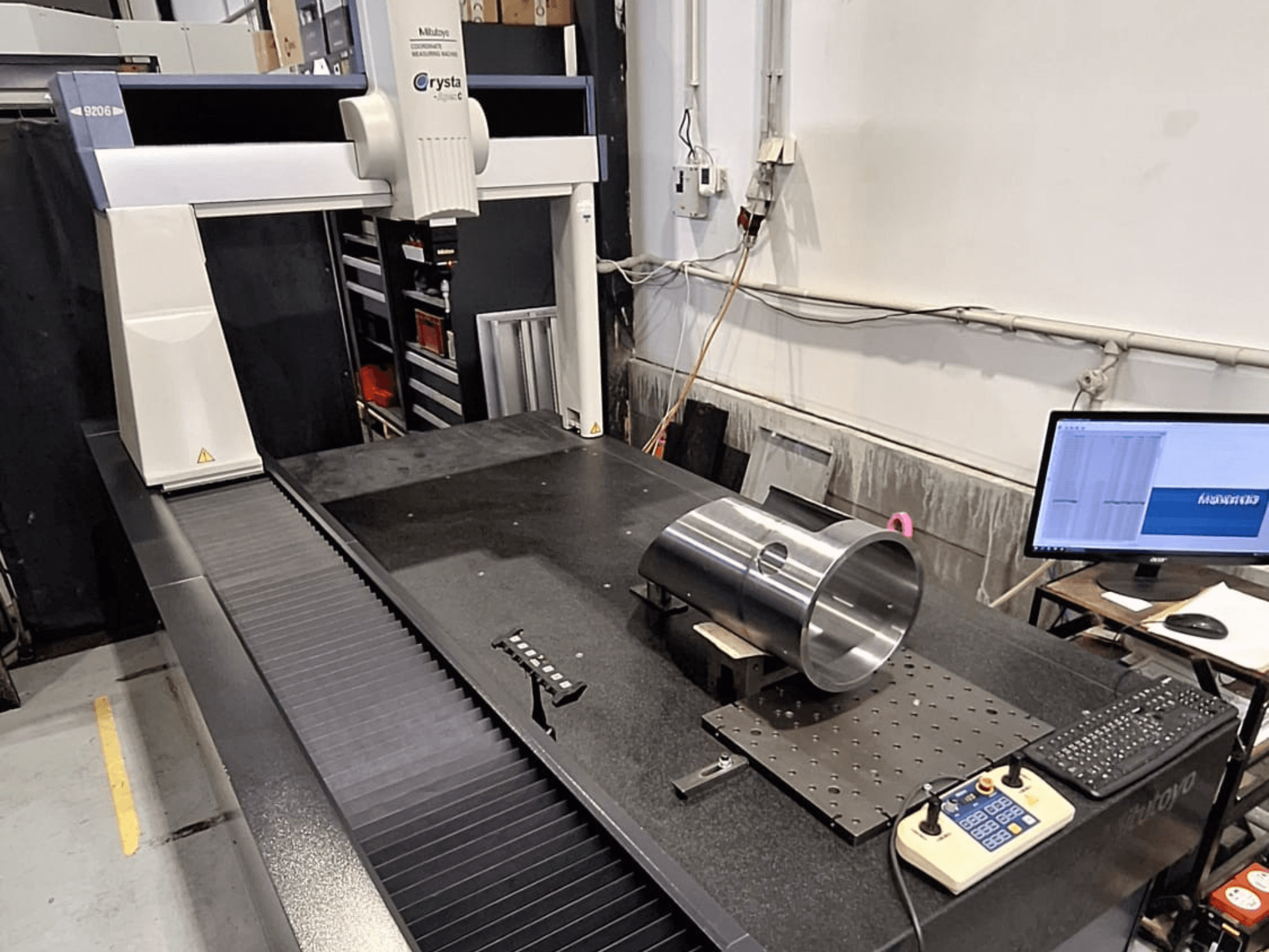 Mitutoyo Crysta-Apex C9206 CMM u prednjem pogledu, mjeri cilindrični metalni dio na crnoj granitnoj površini ploče.