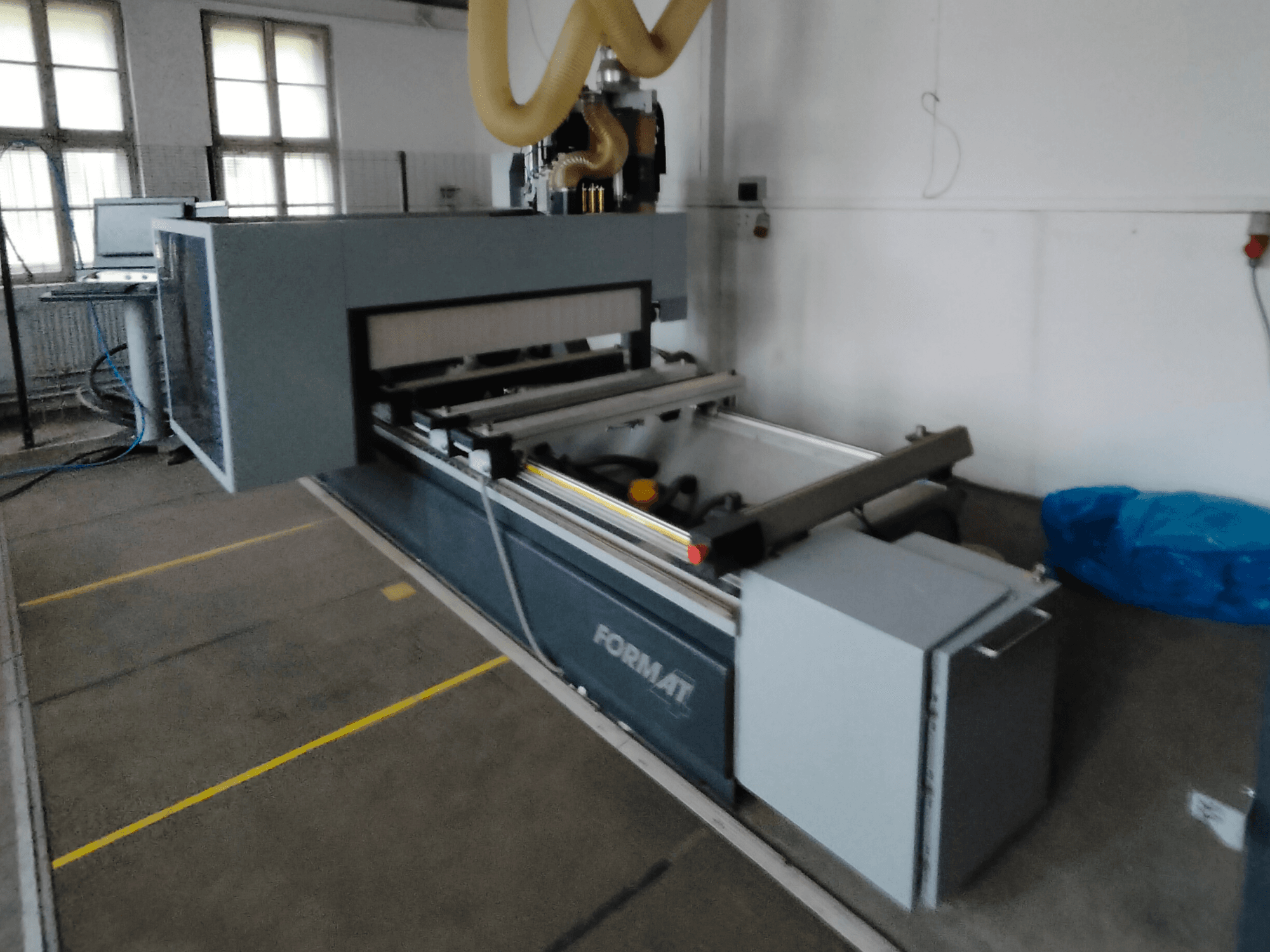 Prednji pogled na CNC stroj Format sa sivim kućištem, s vodećim tračnicama i vidljivom upravljačkom pločom.