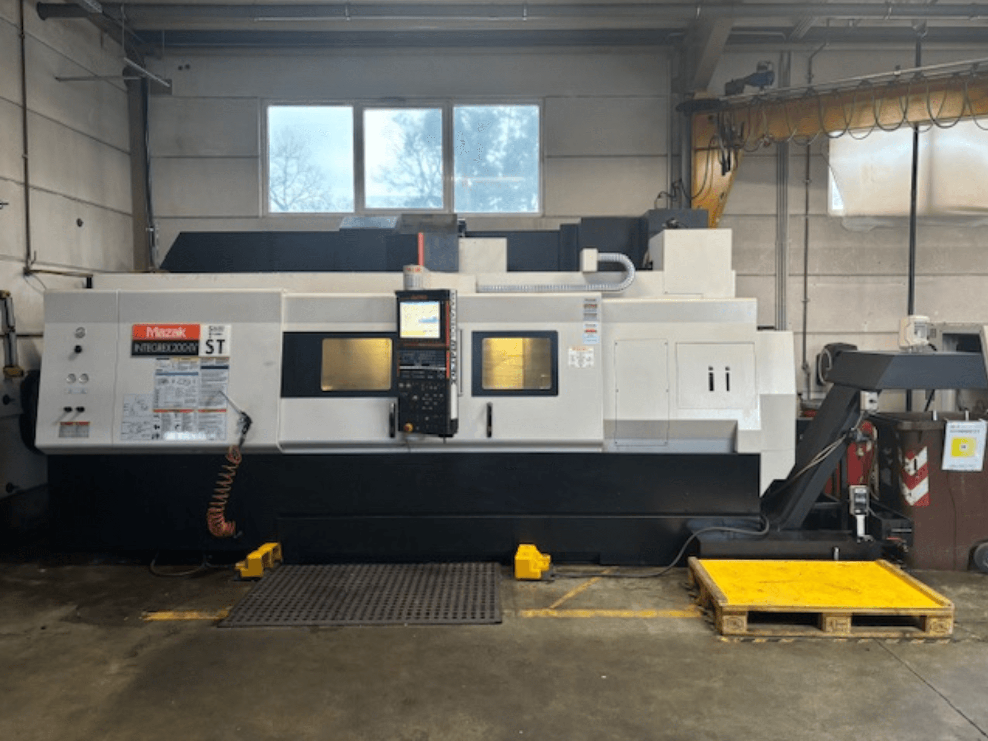 Mazak Integrex 200 SY ST, bočni pogled, prikazuje upravljačku ploču, zaslone rada i vodove rashladne tekućine u radioničkom okruženju.