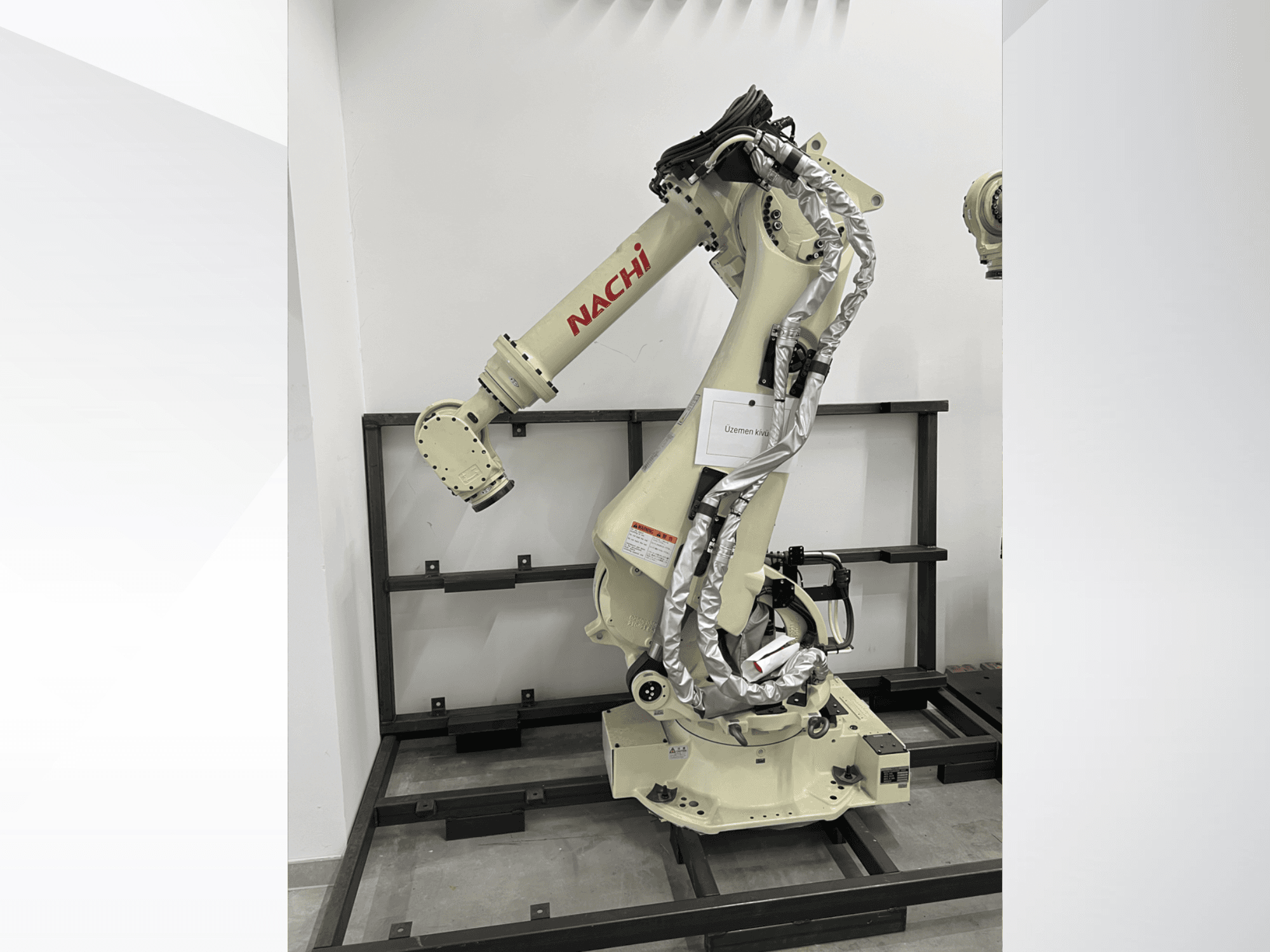 Robotska ruka NACHI SRA166-01 u bočnom pogledu, s fleksibilnim zglobovima, pričvršćenim kabelima i montirana na zaštitni okvir.