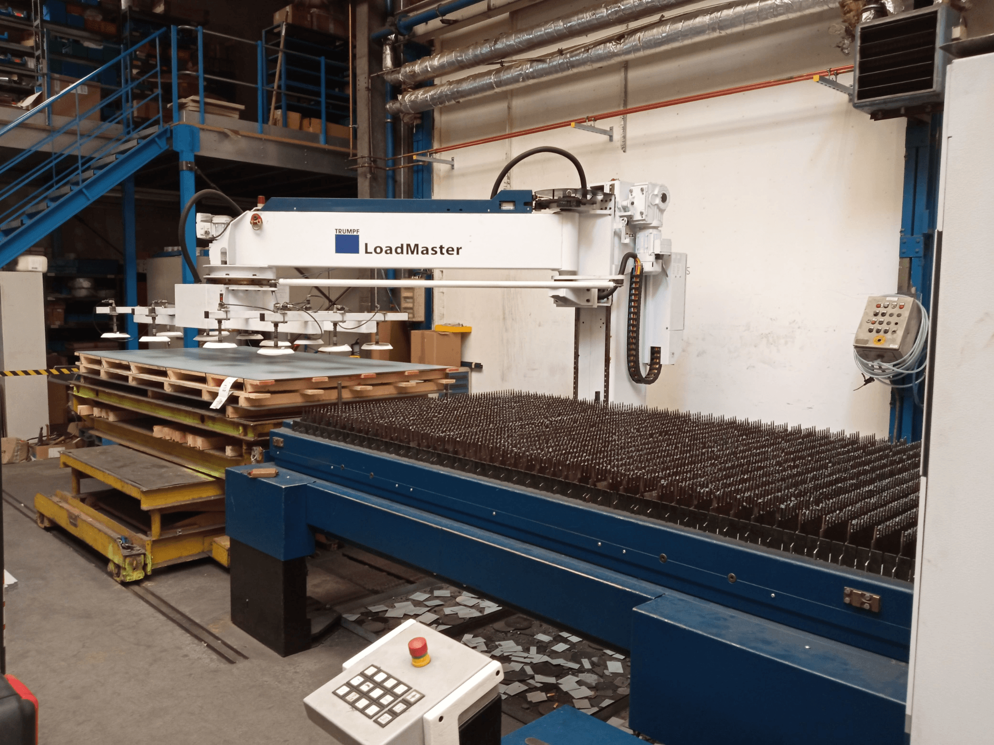 TRUMPF TruLaser 3030 CO2 laserski stroj za rezanje u bočnom pogledu, s LoadMasterom i paletama materijala.