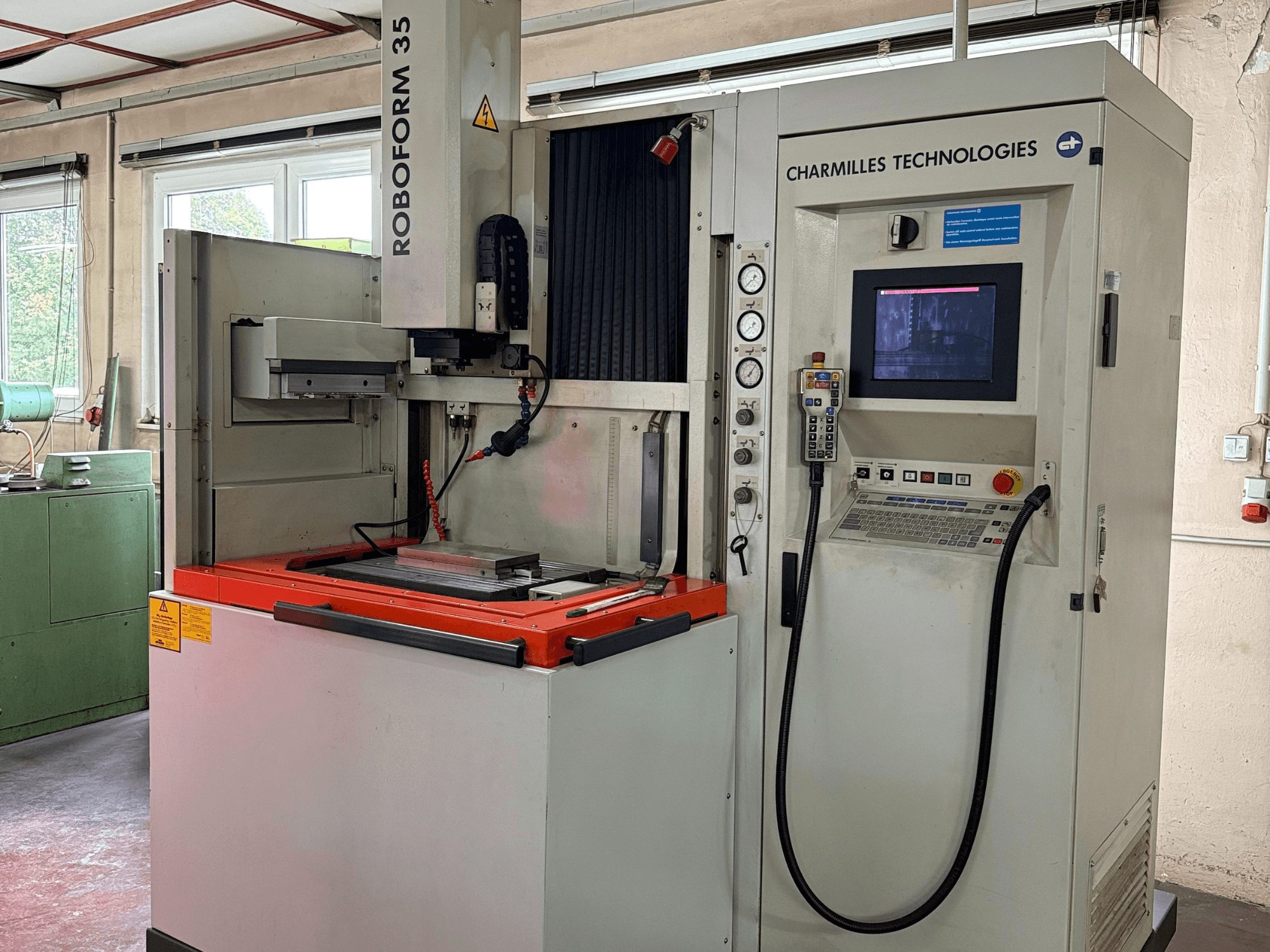 Stroj Charmilles Technologies Roboforn 35, prednji pogled, prikazuje upravljačku ploču, montirane alate i sigurnosne naljepnice.