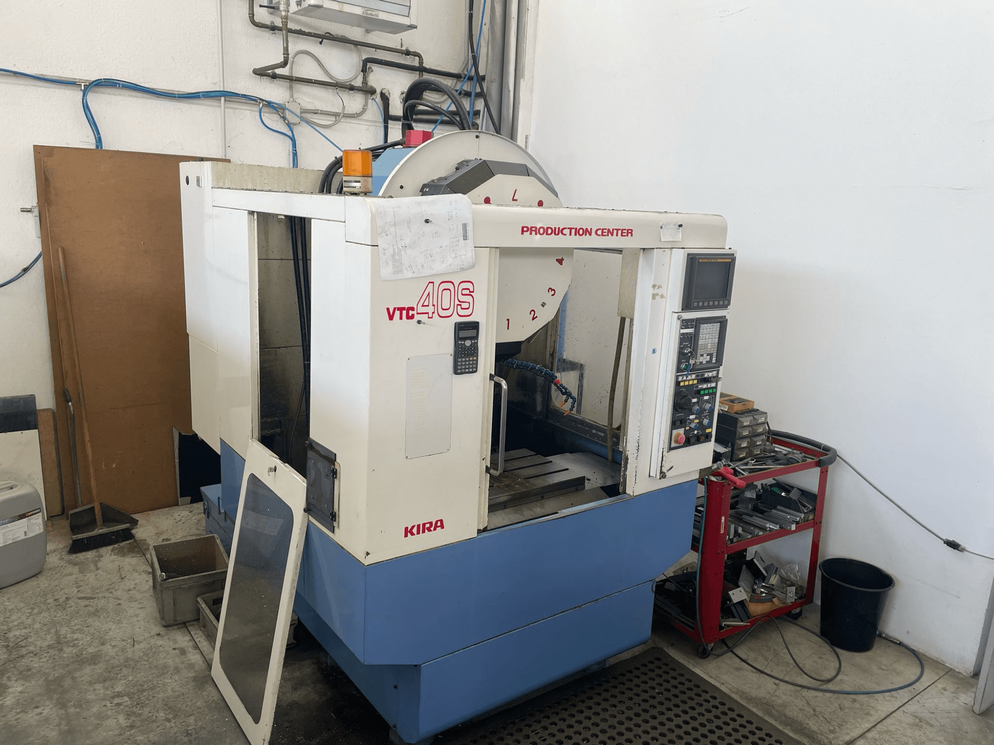 Bočni prikaz obradnog centra KIRA VTC 40S s upravljačkom pločom, otvorenim vratima i alatima na kolicima za pohranu u blizini.