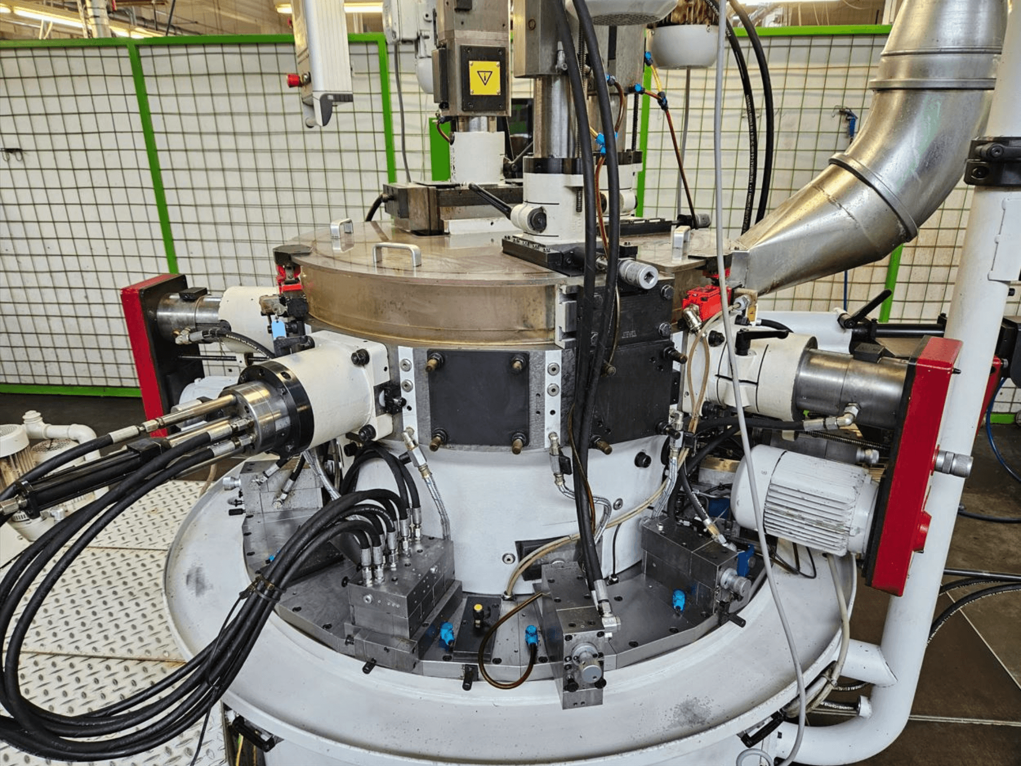 Pogled izbliza na industrijski stroj s hidrauličkim crijevima, metalnim komponentama i rotirajućom bazom. Nije vidljiva marka.