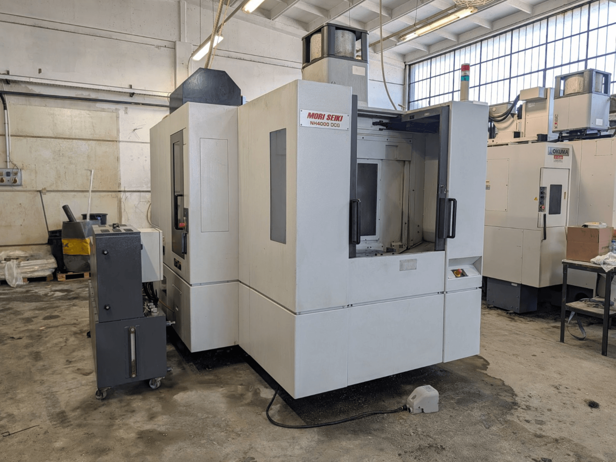 MORI SEIKI NH 4000 DCG horizontalni obradni centar, prednji pogled, prikaz upravljačke ploče i radnog prostora, siva i bijela završna obrada.