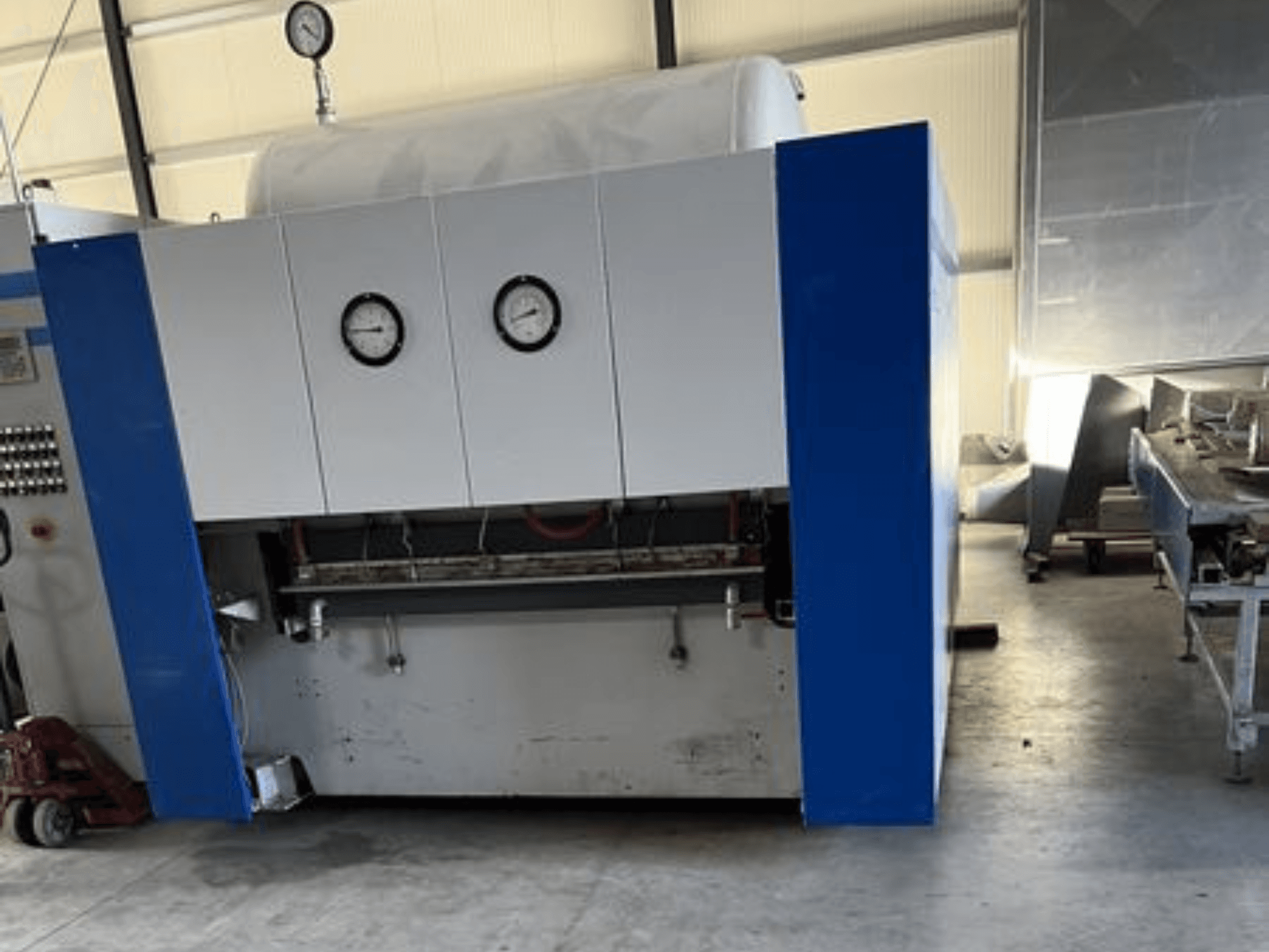 Plavo-bijeli industrijski stroj s dva manometra, prednji pogled, s upravljačkom pločom i susjednom opremom.