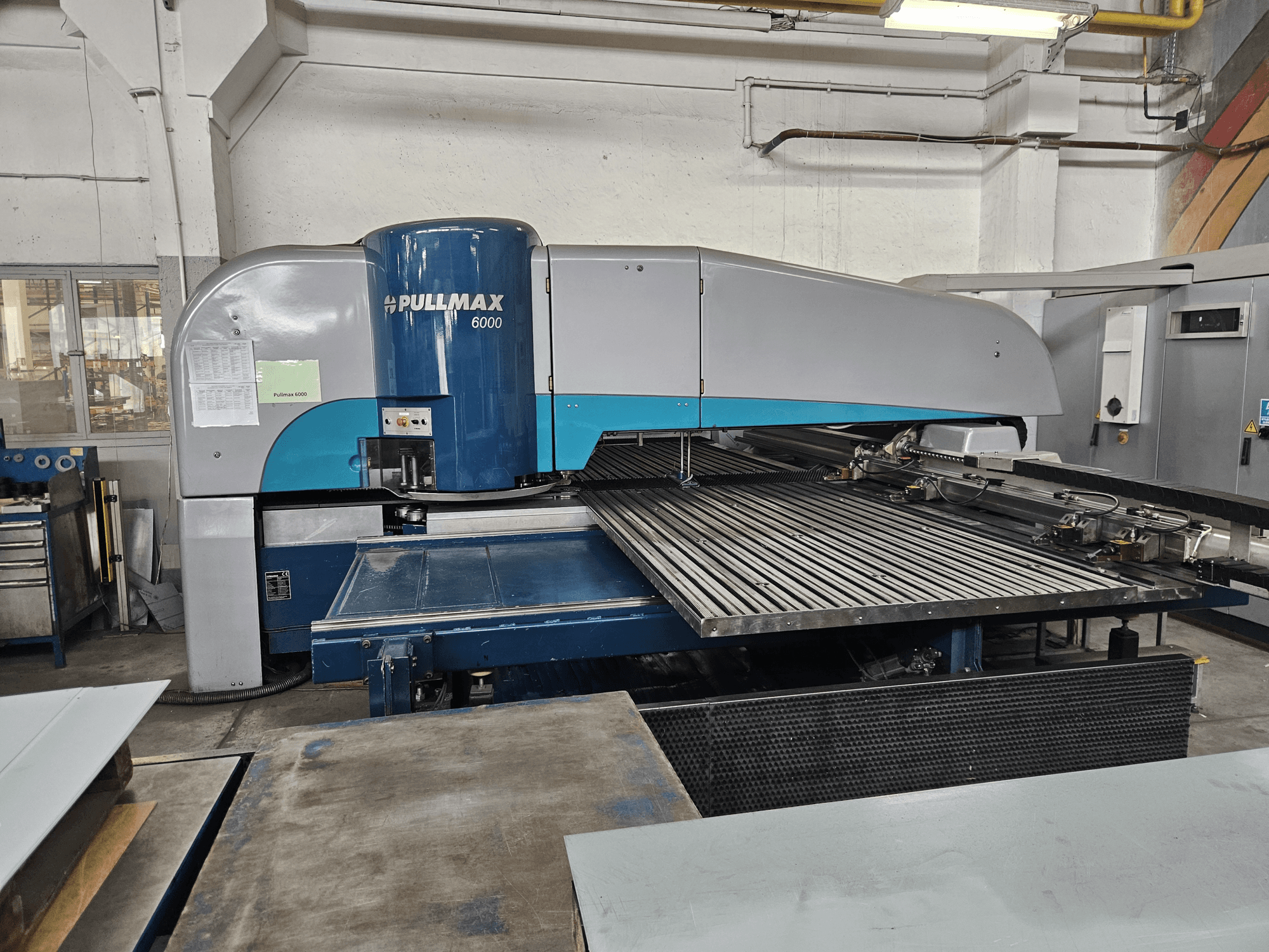 Prednji pogled na CNC stroj za probijanje Pullmax 6000, s velikom ravnom platformom i metalnim okvirom u radioničkom okruženju.