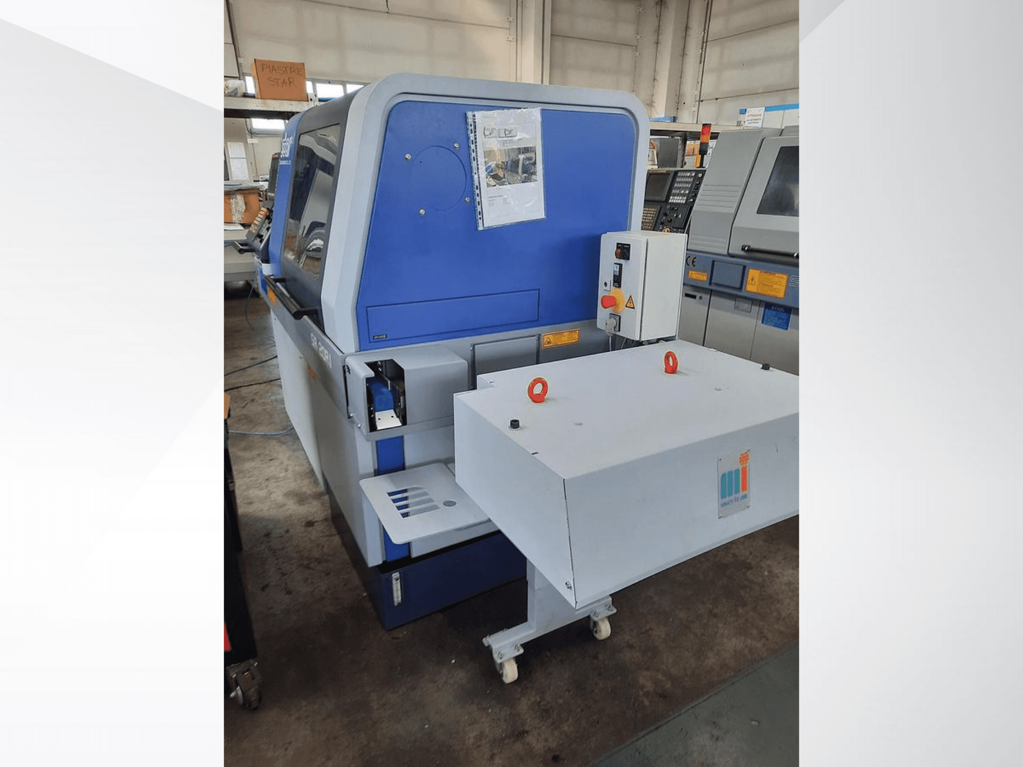 Plavi industrijski stroj s bijelim transporterom, s prikazom upravljačke ploče i priloženih sigurnosnih značajki, bočni pogled.
