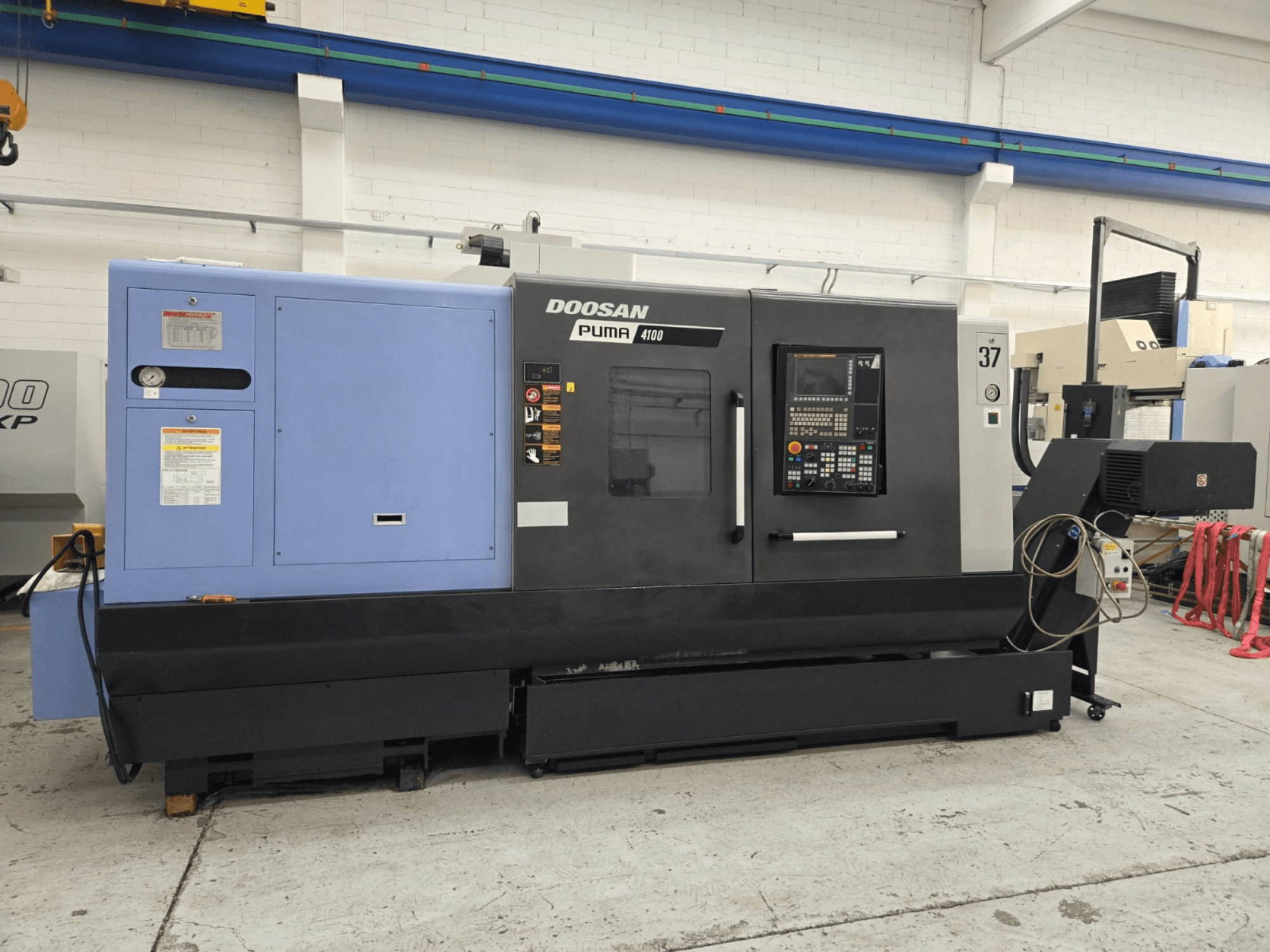 Doosan Puma 4100 CNC tokarski stroj, pogled sprijeda; ima upravljačku ploču, plavi pogonski agregat i detaljne naljepnice za upute o radu.