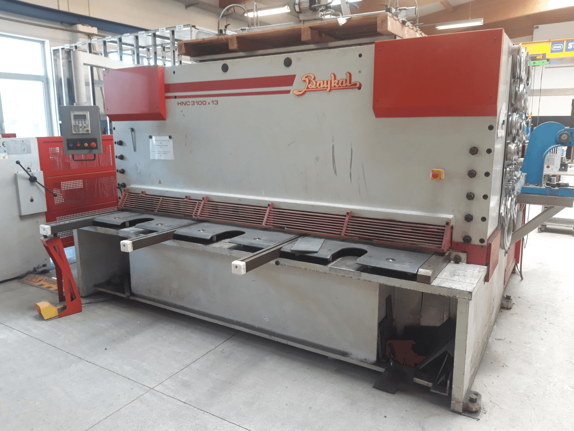 Prednji pogled na CNC škare Baykal HNC 3100x13, s upravljačkom pločom, prostorom za rezanje metala i prostorom za prikupljanje otpada.