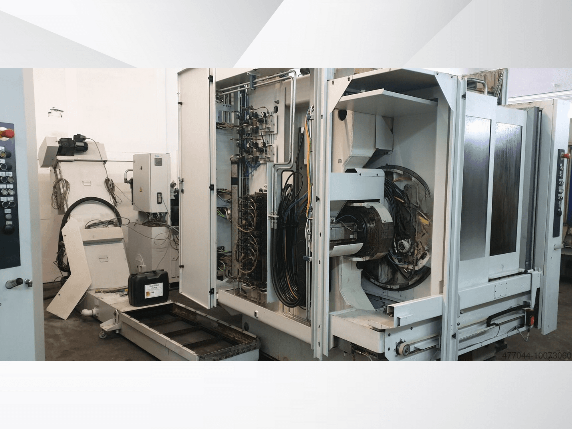 Industrijski strojevi s izloženim ožičenjem, upravljačkom pločom i mehaničkim komponentama; bočni pogled na složeni stroj.