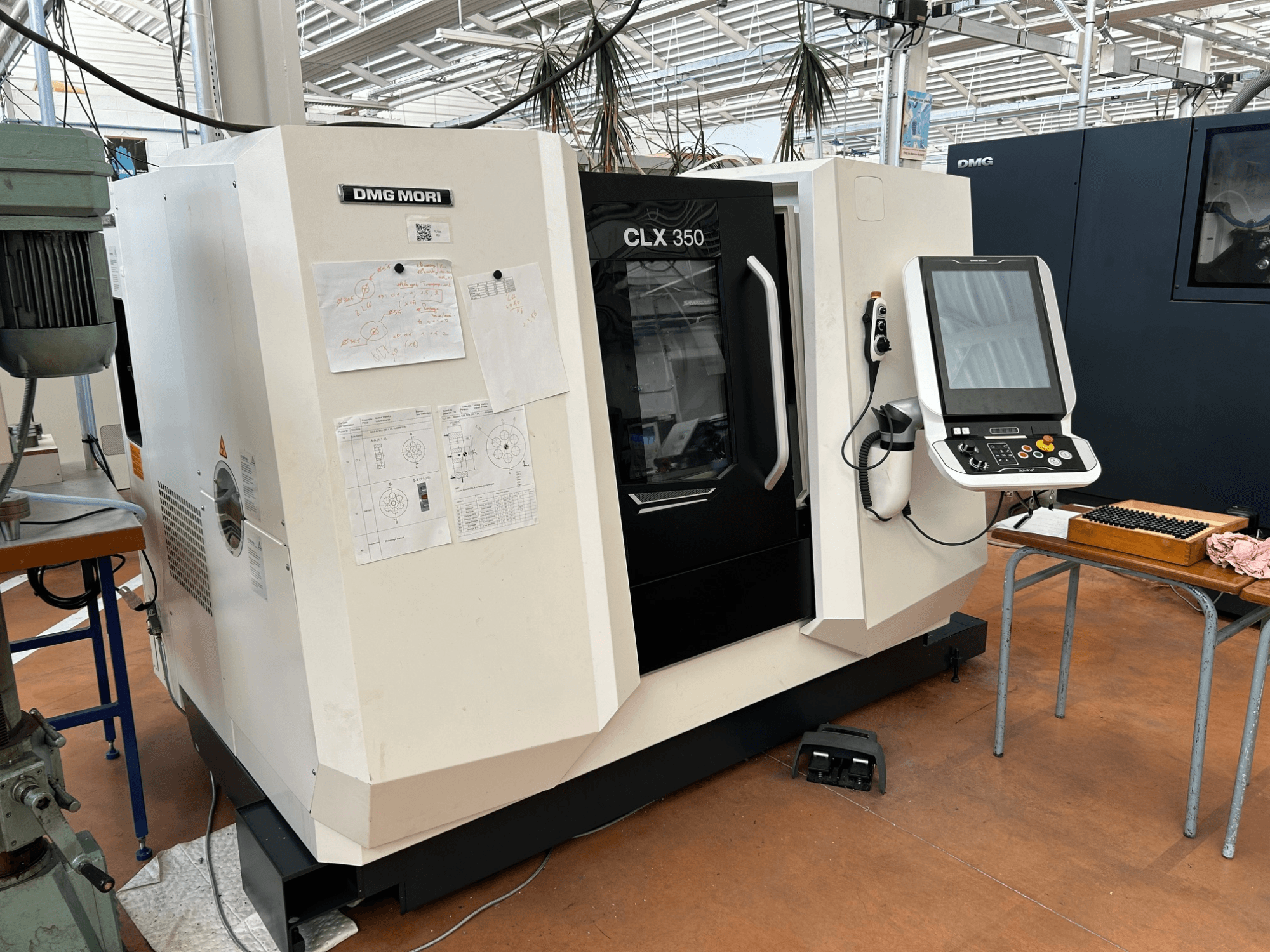 Horizontalni tokarski stroj DMG MORI CLX 350 V4, prednji pogled s priloženom upravljačkom pločom i tehničkom dokumentacijom.