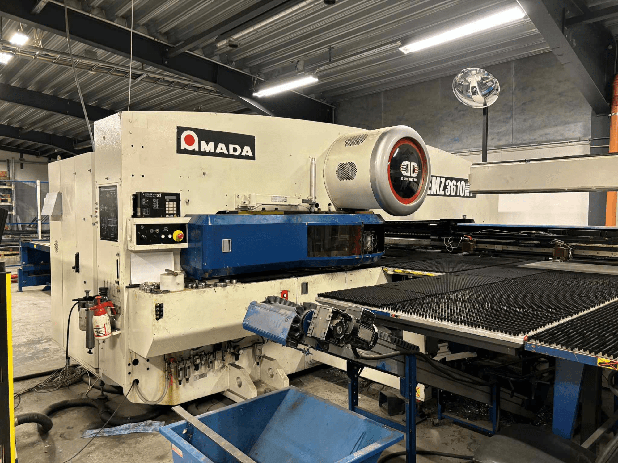 Amada EMZ3610H bušilica gledana sprijeda; ima operativne kontrole, plavi krevet i sigurnosnu opremu.