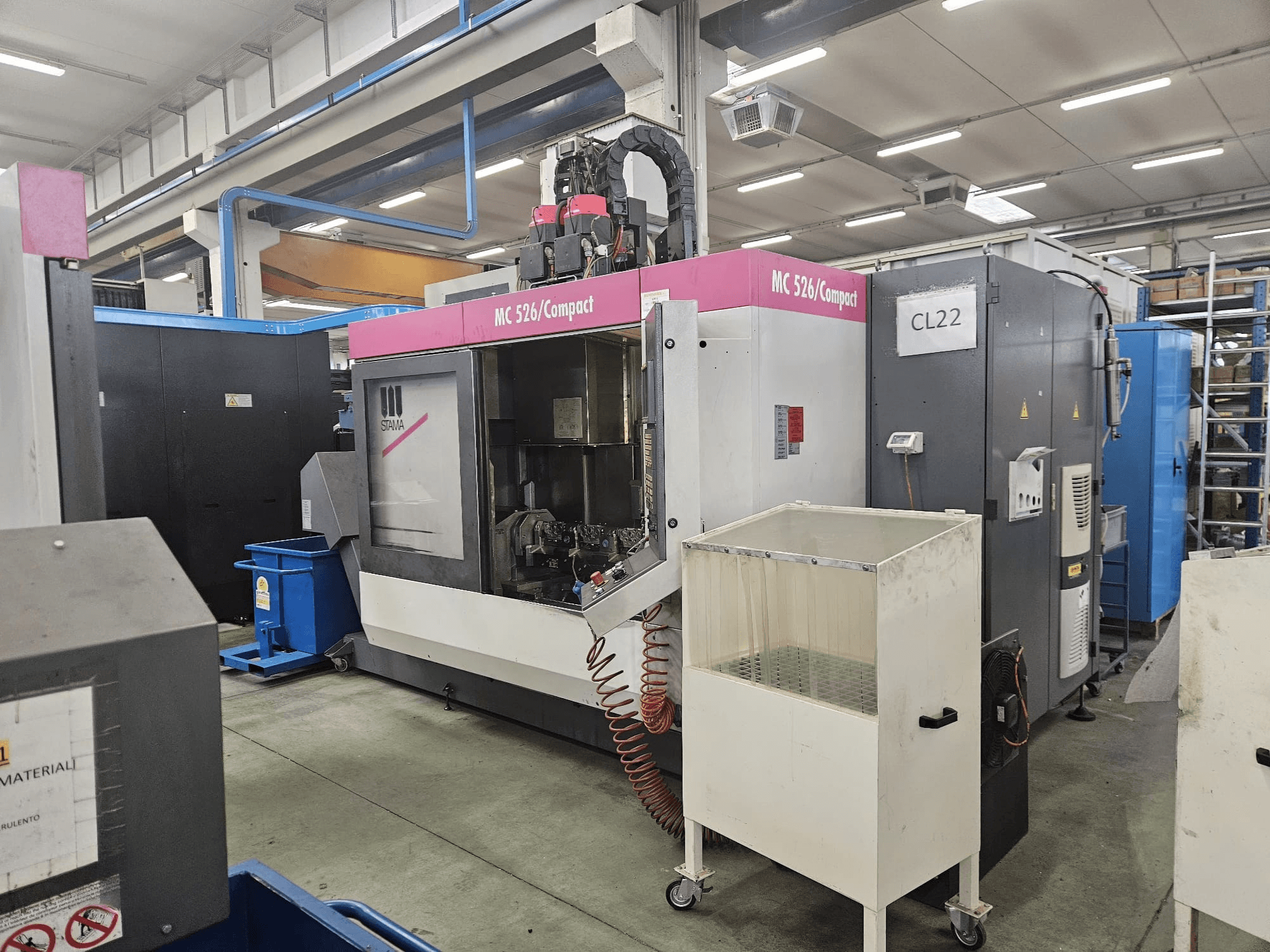 MC 526 Kompaktni CNC stroj tvrtke Stama, bočni pogled, prikazuje upravljačku ploču, spremnik rashladne tekućine i susjedne strojeve.