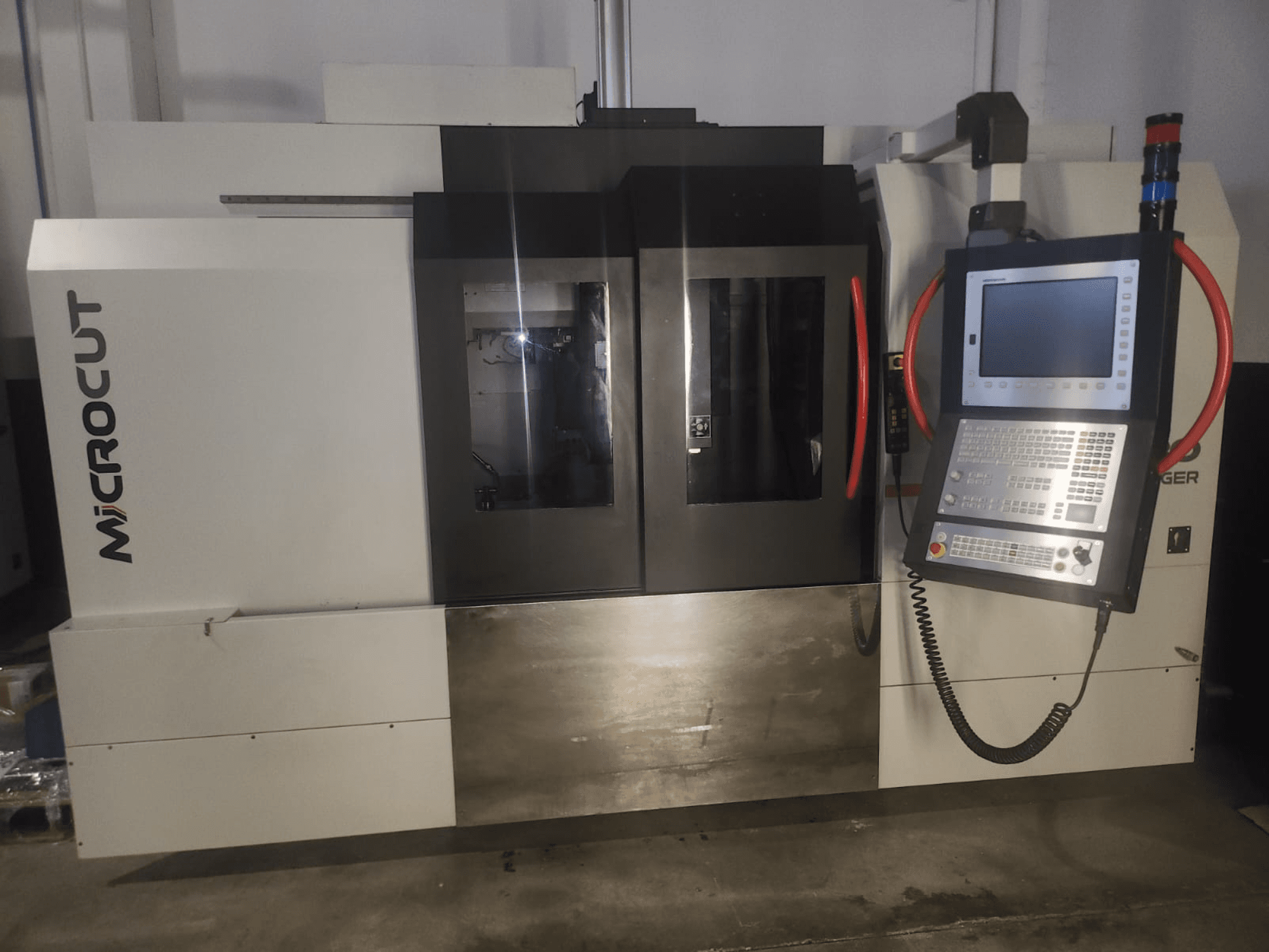 CNC stroj za mikrorezanje gledan sprijeda; ima upravljačku ploču, dvostruke prozore, industrijski dizajn i metalnu završnu obradu.