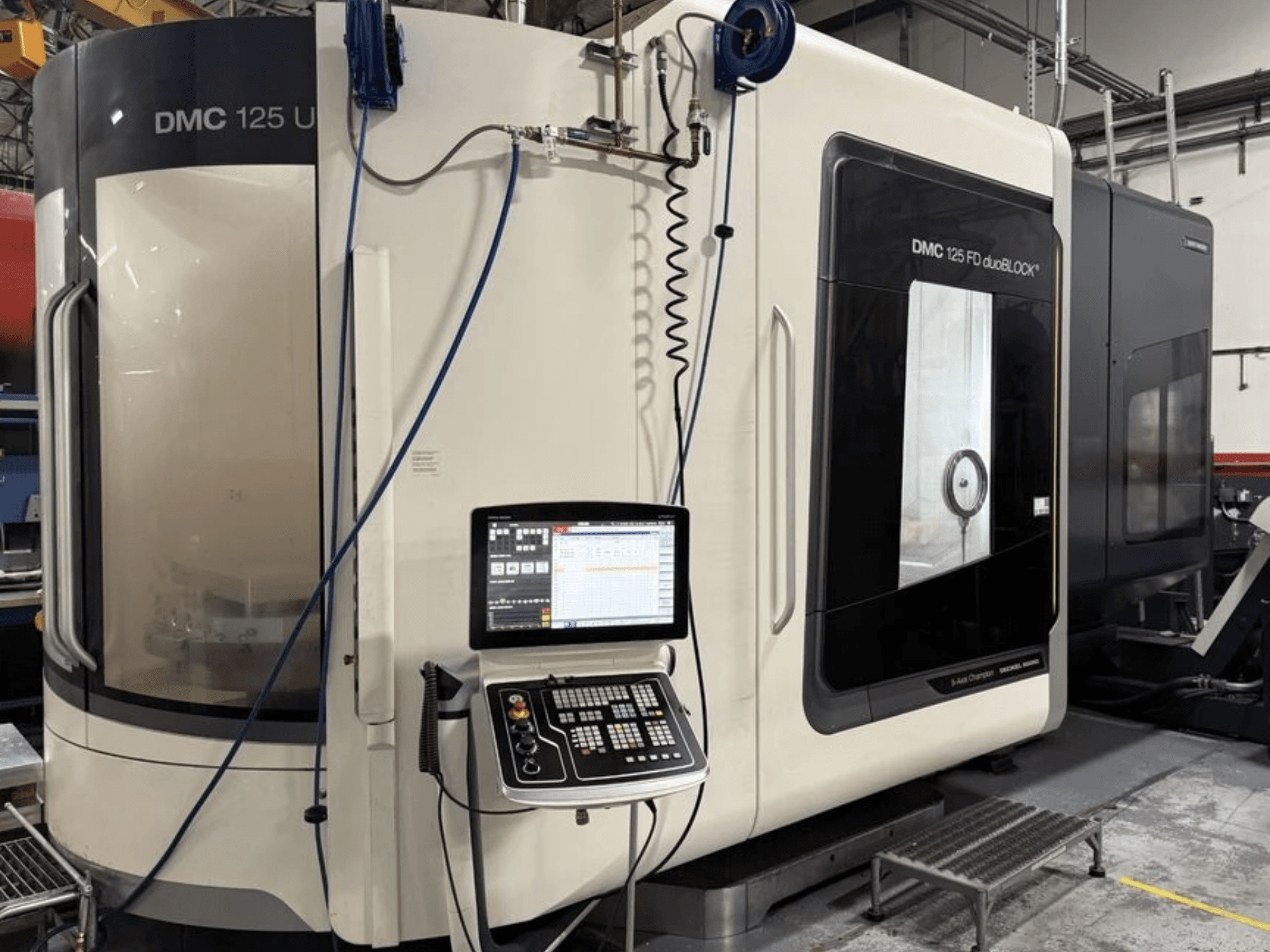 Univerzalni obradni centar DMG MORI DMC 125 U duoBLOCK, prednji pogled s upravljačkom pločom i reflektirajućim površinama.