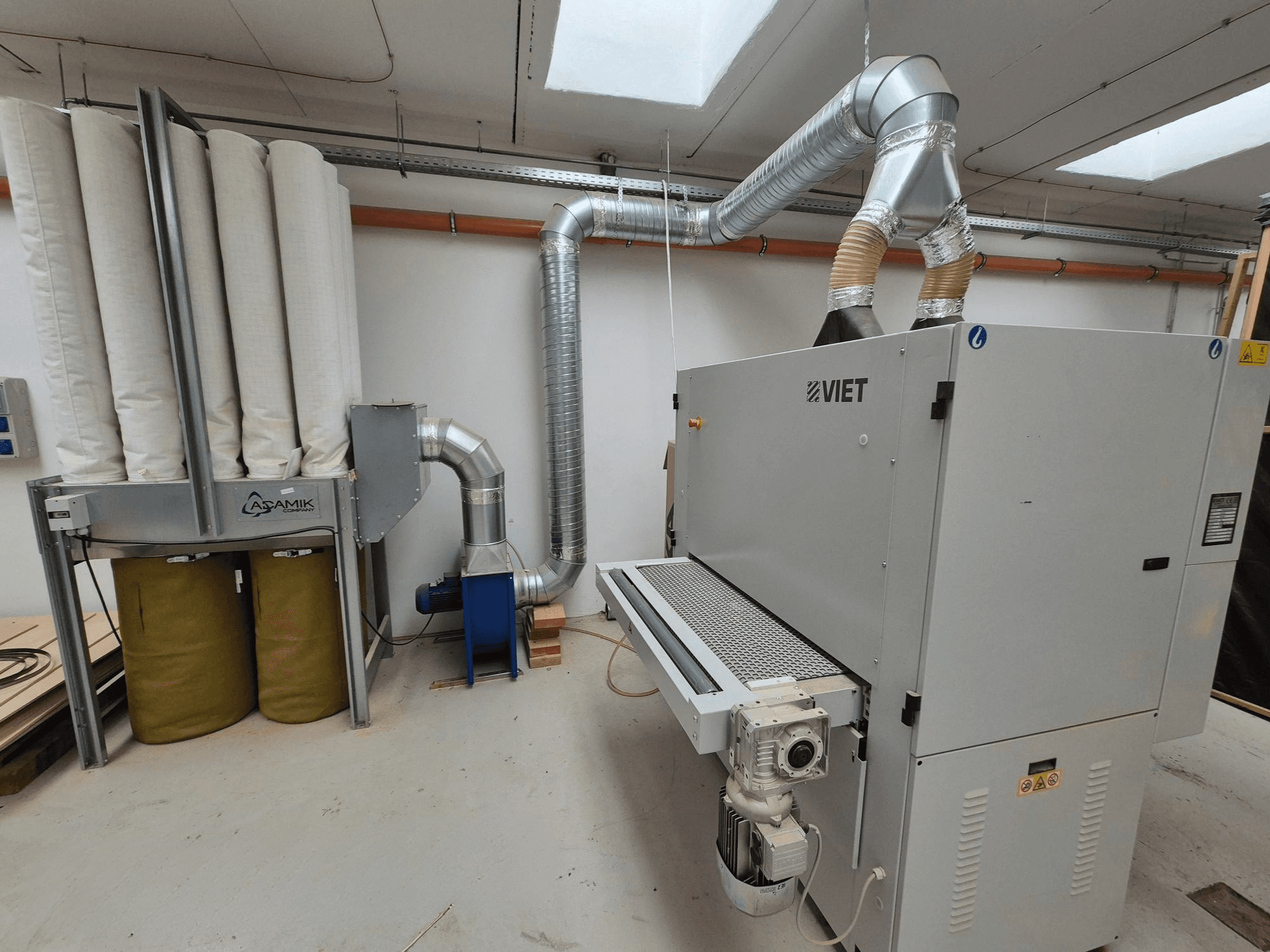 Vijetnamski sustav za usisavanje prašine s cilindričnim filterima i srebrnim ispuhom, gledan sprijeda u radioničkom okruženju.