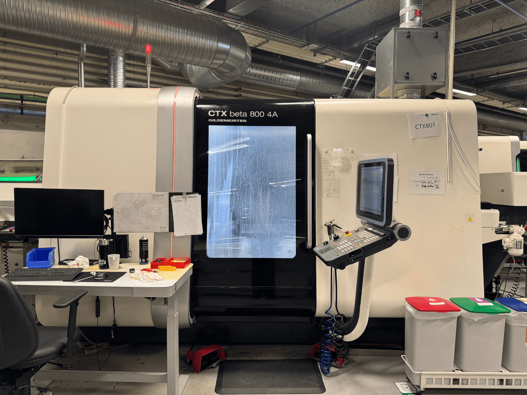Stroj CTX beta 800 4A s upravljačkom pločom i monitorom, bočni pogled, u radionici s uredskim postavom i kantama za smeće u boji.