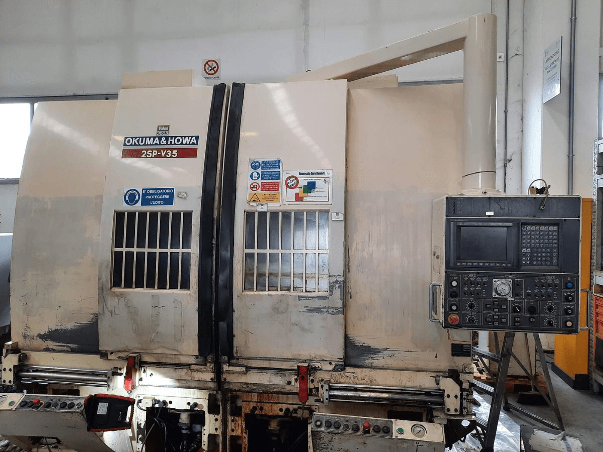 OKUMA & HOWA 2SP-V35 CNC stroj gledan sprijeda, s upravljačkom pločom s raznim gumbima i sigurnosnim naljepnicama.